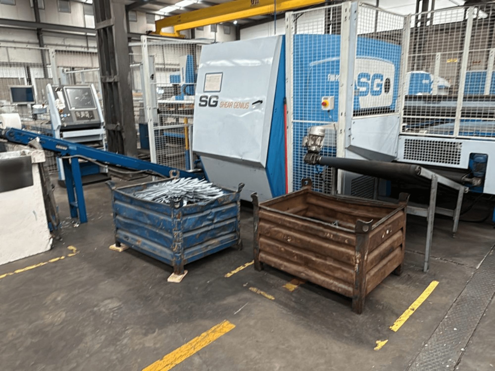 Machine de poinçonnage et de pliage Finn-Power SG6 12.61, vue de face avec des conteneurs métalliques à côté dans un atelier.