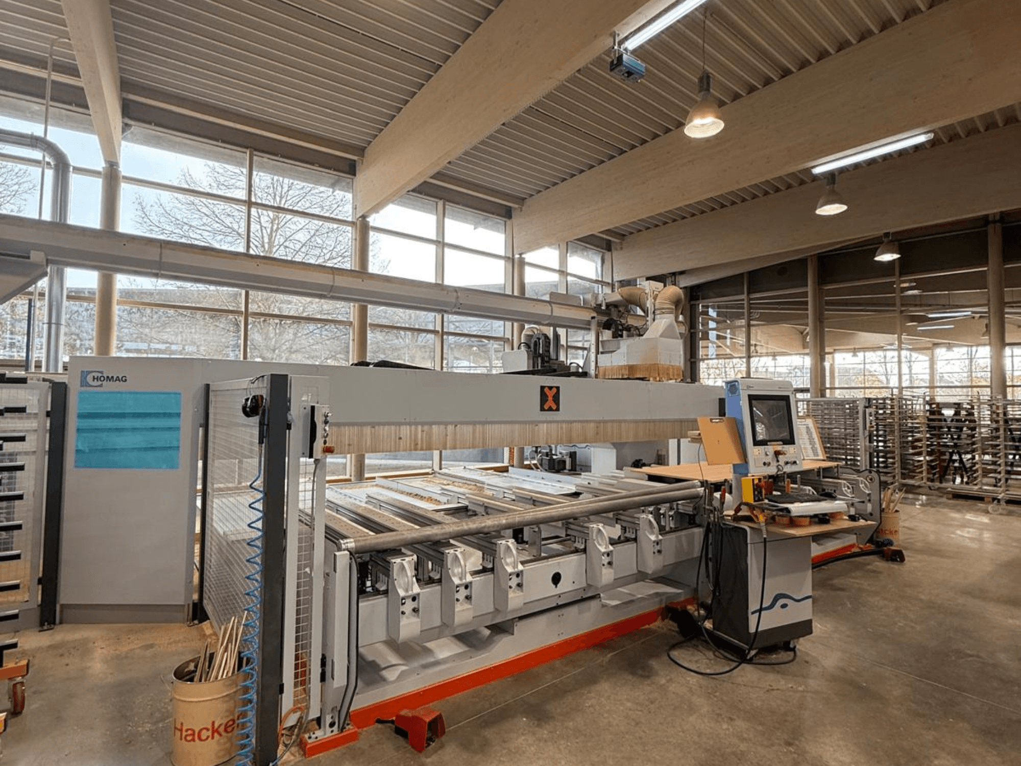 Machine CNC HOMAG dans un atelier, vue de face, présentant un panneau de commande et plusieurs emplacements d'outils pour le travail du bois de précision.