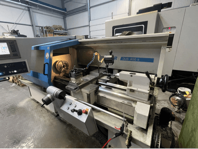 Tour CNC DUS 400 ti vu de face, avec panneau de commande, porte-outils et espace de travail éclairé.