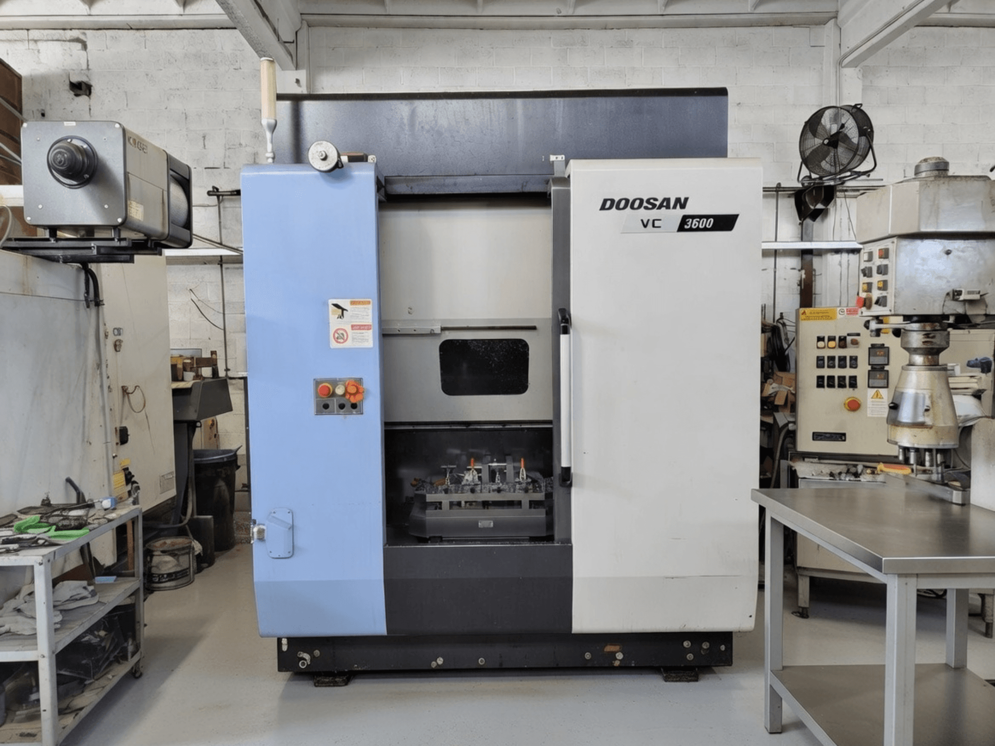 Centre d'usinage vertical DOOSAN VC 3600 vu de face, avec panneau de commande et porte ouverte révélant l'espace de travail.