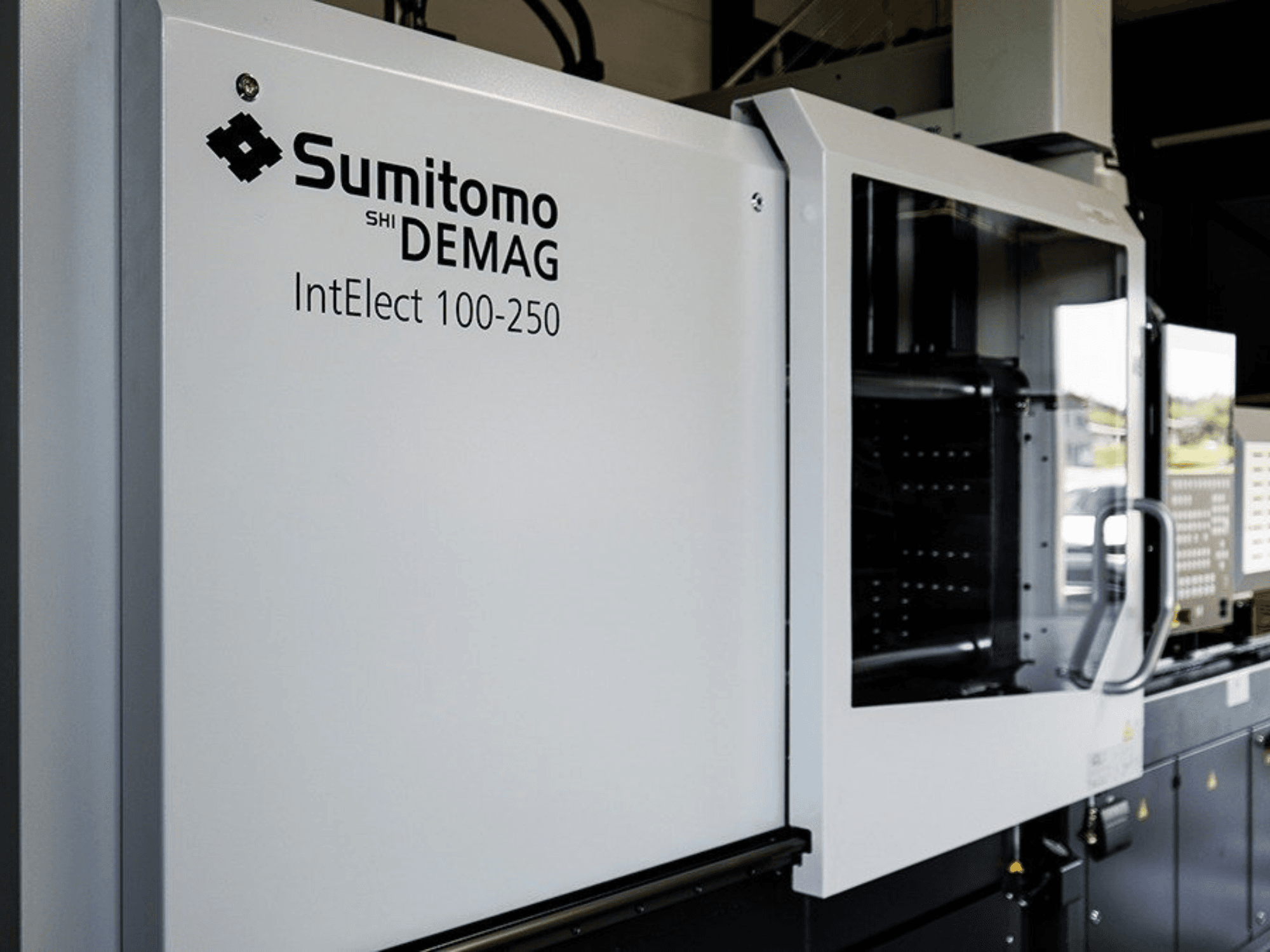 Vue de face de la presse à injection électrique SUMITOMO SHI DEMAG IntElect 100/250, avec son panneau de commande et ses dispositifs de sécurité.