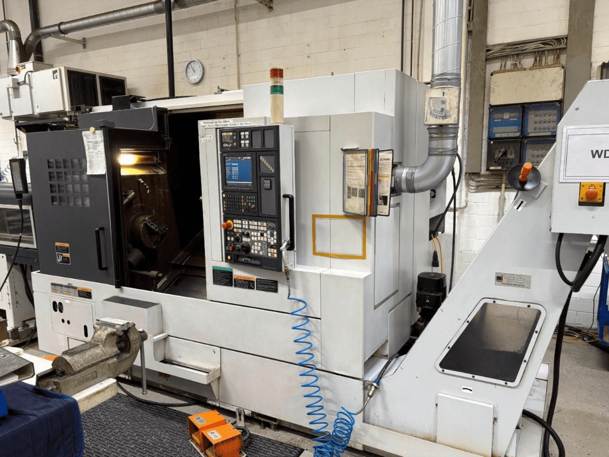 Centre de tournage-fraisage MORI SEIKI NL 2500 SY, vue de face, montrant le panneau de commande et la zone d'usinage. Système d'arrosage et accessoires visibles.