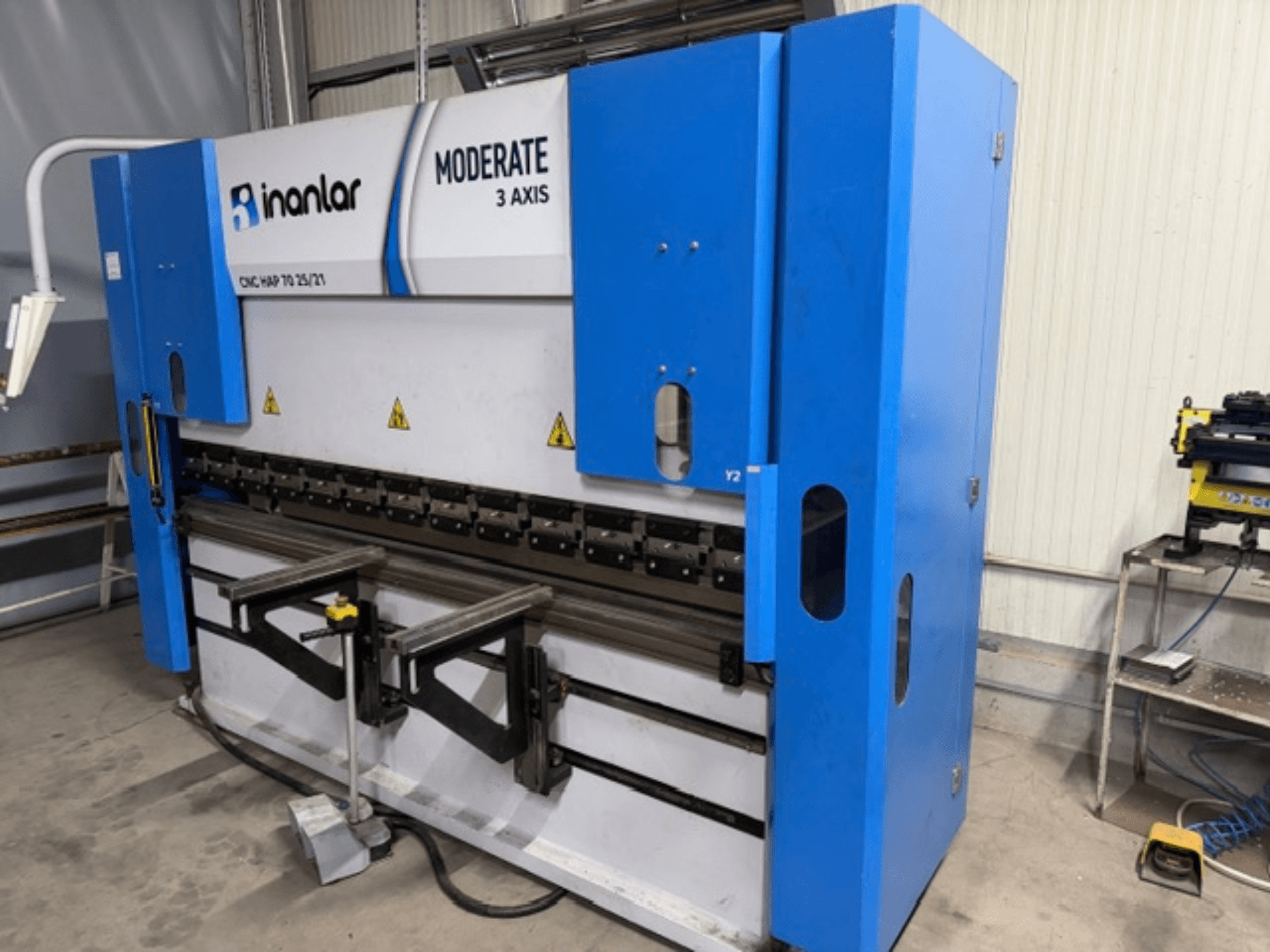 Machine CNC 3 axes modérée Inanlar en bleu, vue de face, avec leviers de commande et étiquettes de sécurité visibles sur le corps.