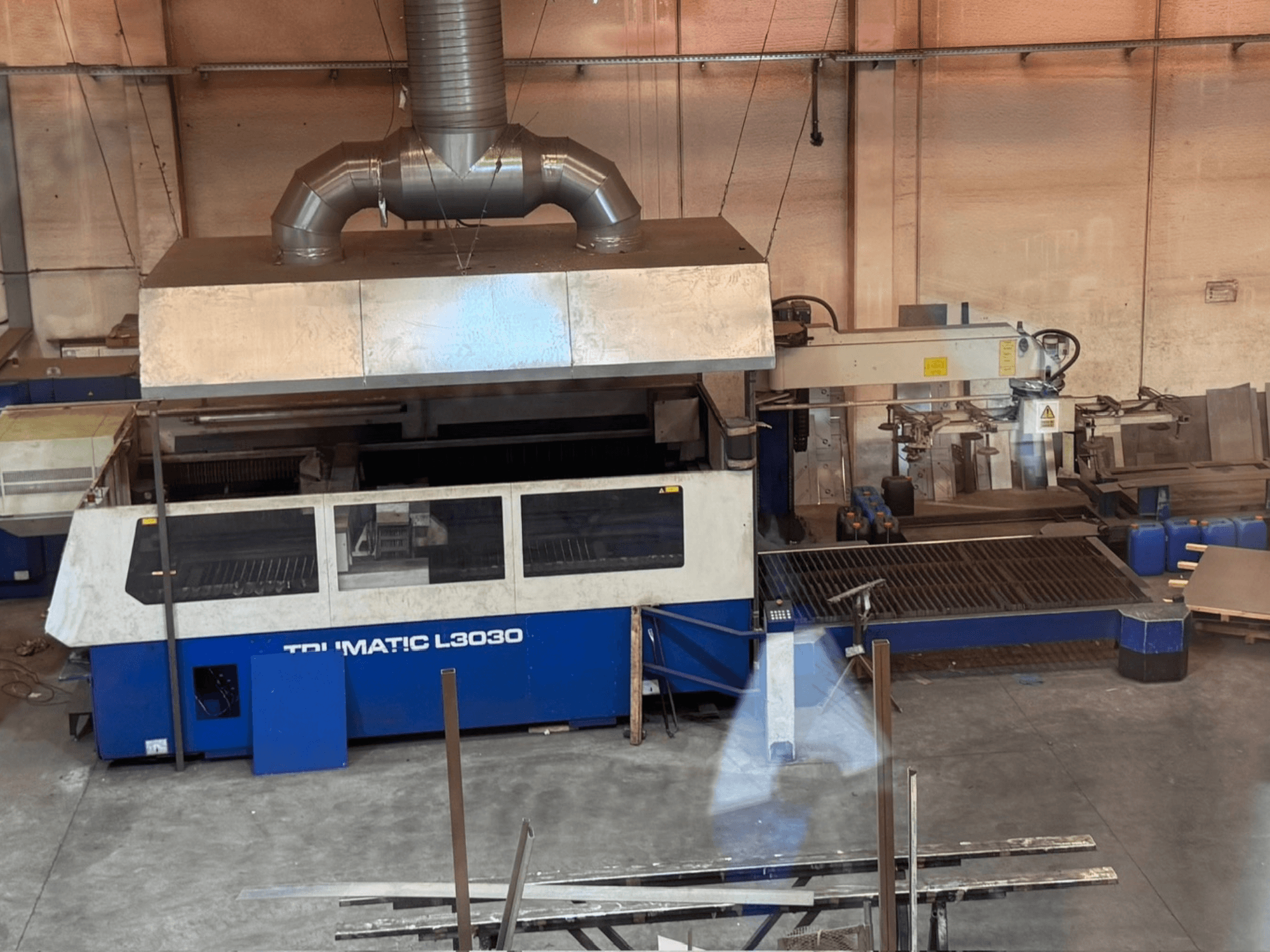 Machine de découpe au laser CO₂ TRUMPF TRUMATIC L3030 dans un atelier, vue de face montrant le panneau de commande et le plateau de découpe.