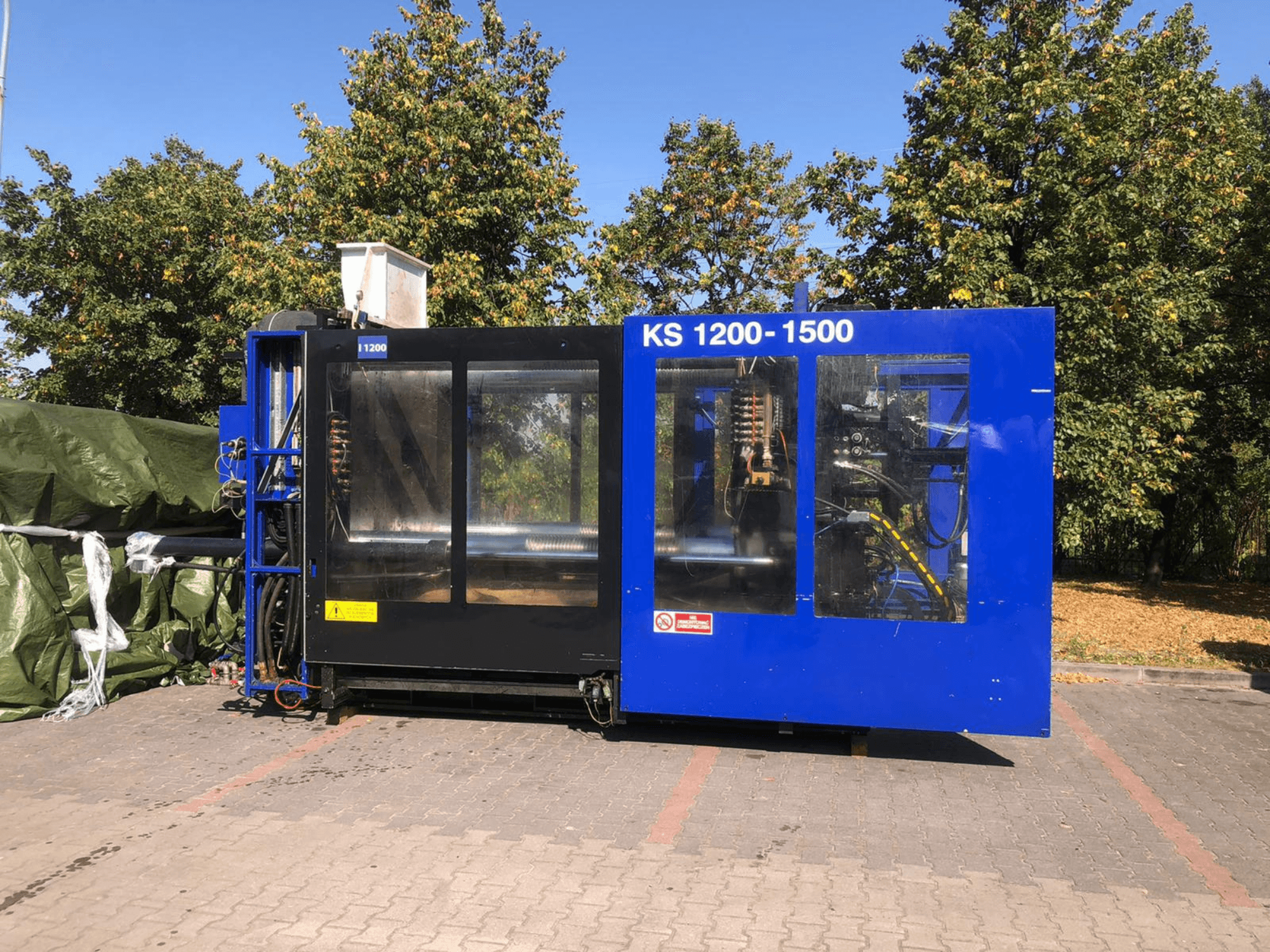 Machine hydraulique de moulage par injection ITALTECH KS 1200 8300 ES, vue latérale, présentant les commandes et les détails de la machine dans un parc.