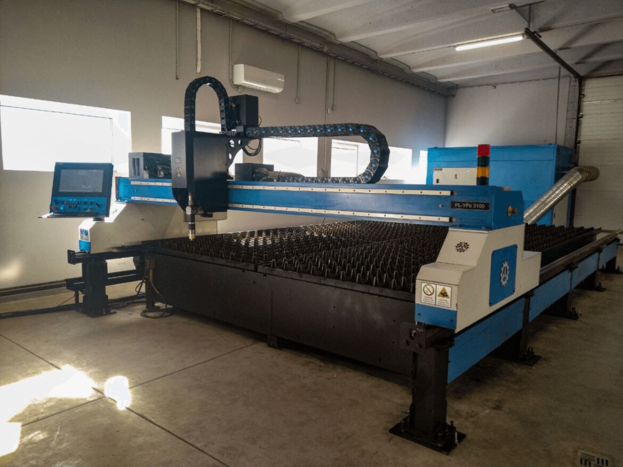 Machine de découpe CNC PL-YP© 3100 avec écran, vue de face, dotée d'un banc de découpe métallique et d'un système de guidage précis des buses.