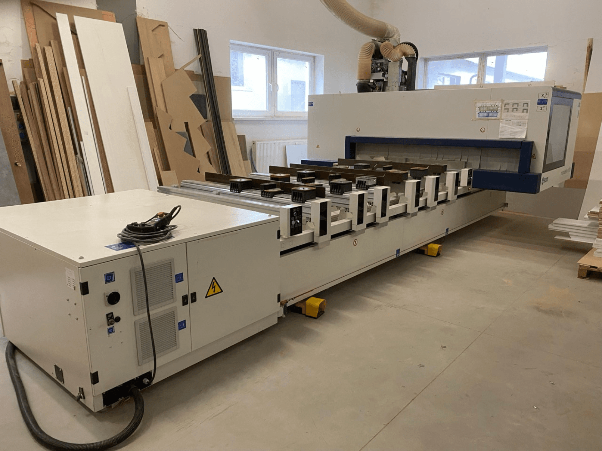 Centre d'usinage CNC SCM Morbidelli Author M100 dans un atelier, vue de face montrant le panneau de commande et le système d'aspiration des poussières.