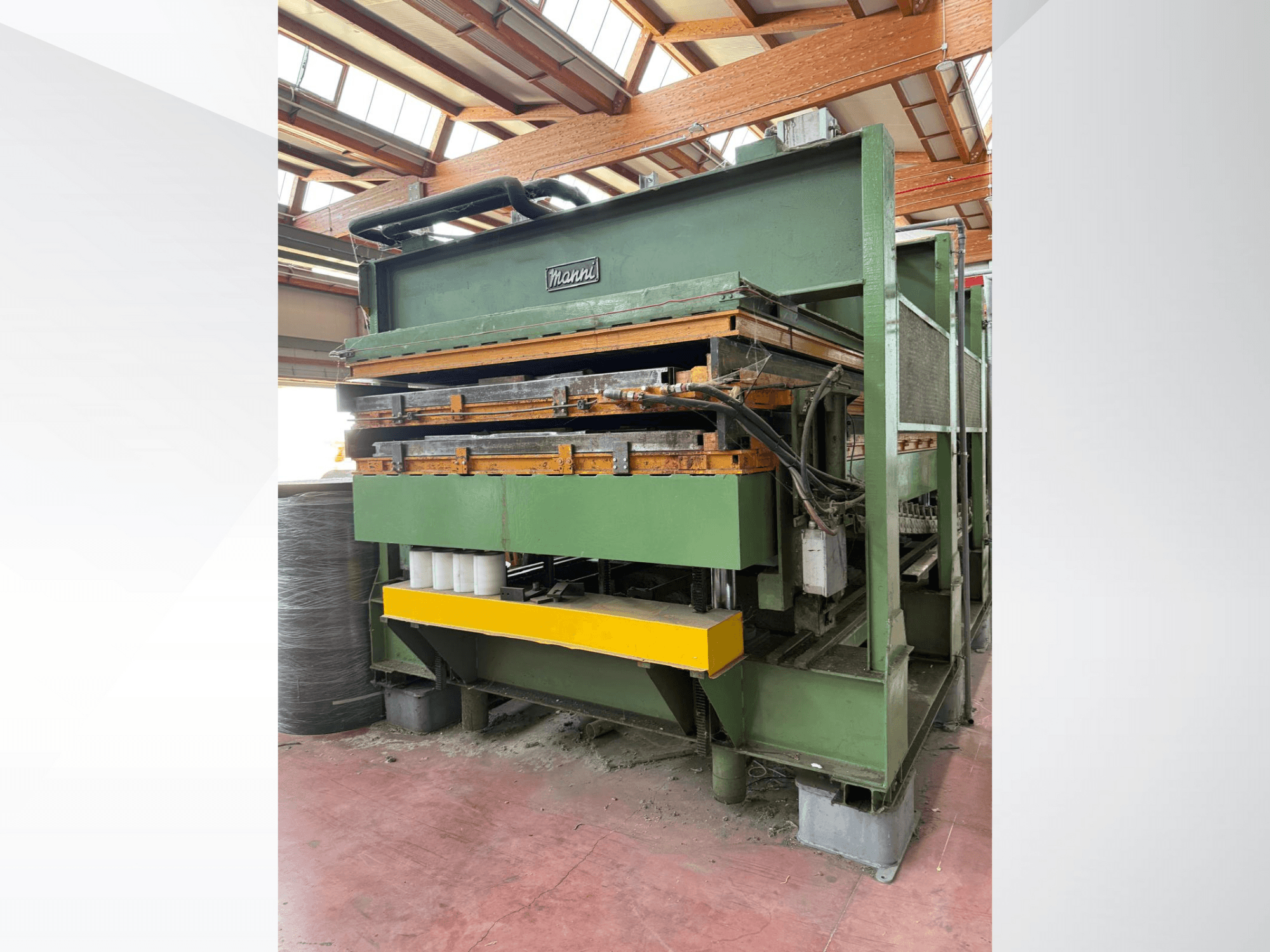 Presse hydraulique Manni, vue de côté, avec corps en métal vert, base jaune et plusieurs lignes hydrauliques visibles.