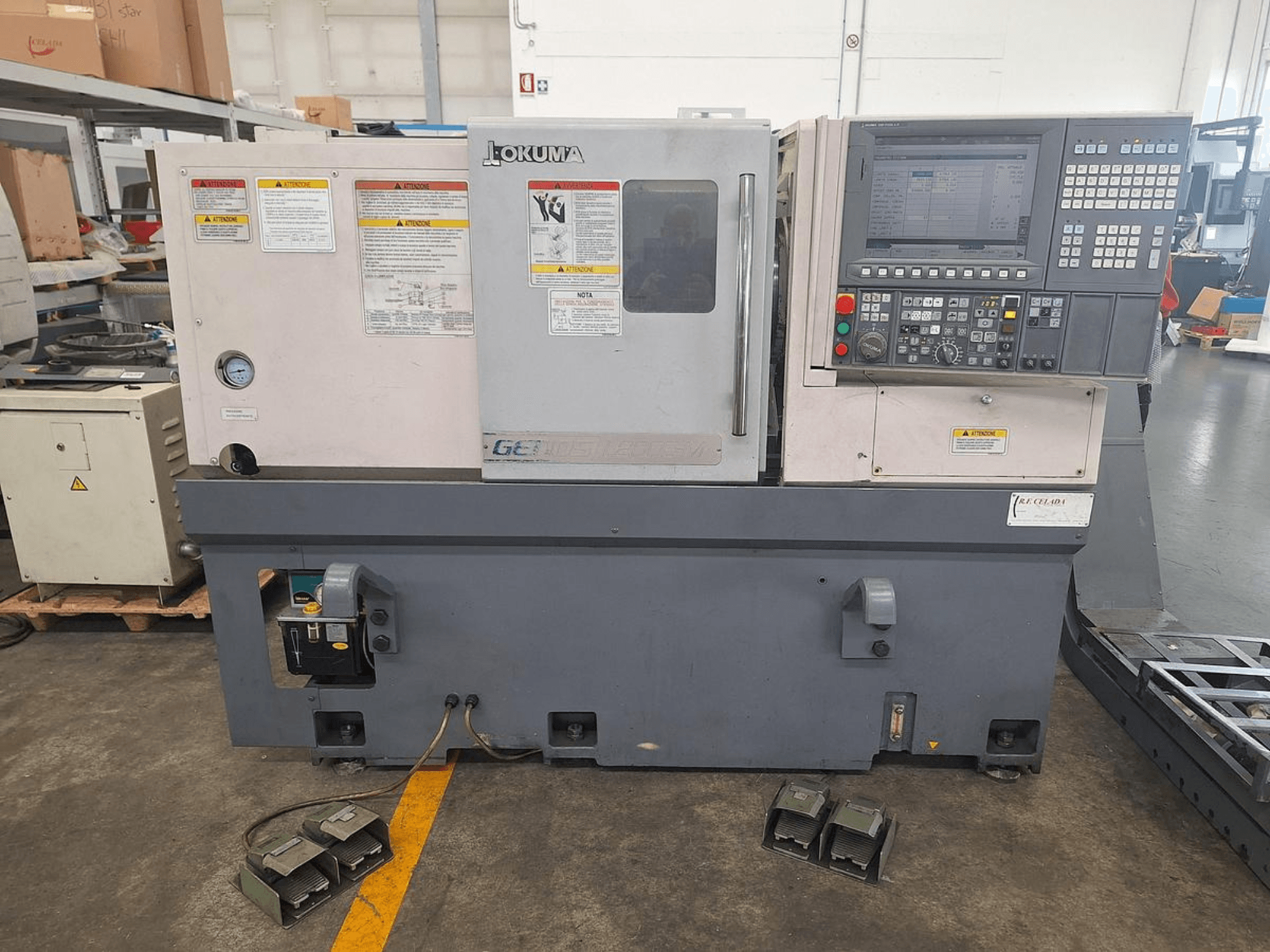 Tour horizontal Okuma GENOS L200E-M en vue latérale ; panneau de commande, avertissements de sécurité et pédales.