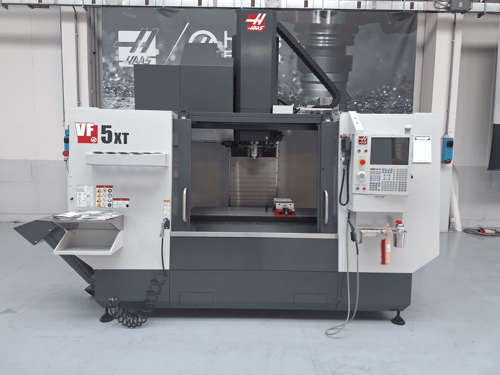 Centre d'usinage vertical HAAS VF-5/50XT, vue de face, présentant le panneau de commande, la zone de la broche et le magasin d'outils.