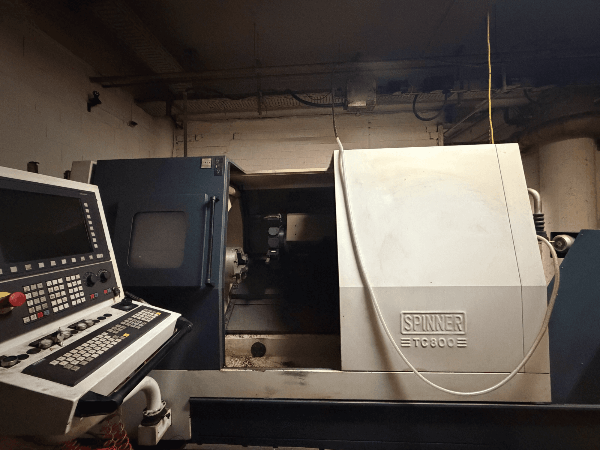 Tour horizontal SPINNER TC800, vue de face avec panneau de commande visible et intérieur de la machine légèrement exposé.