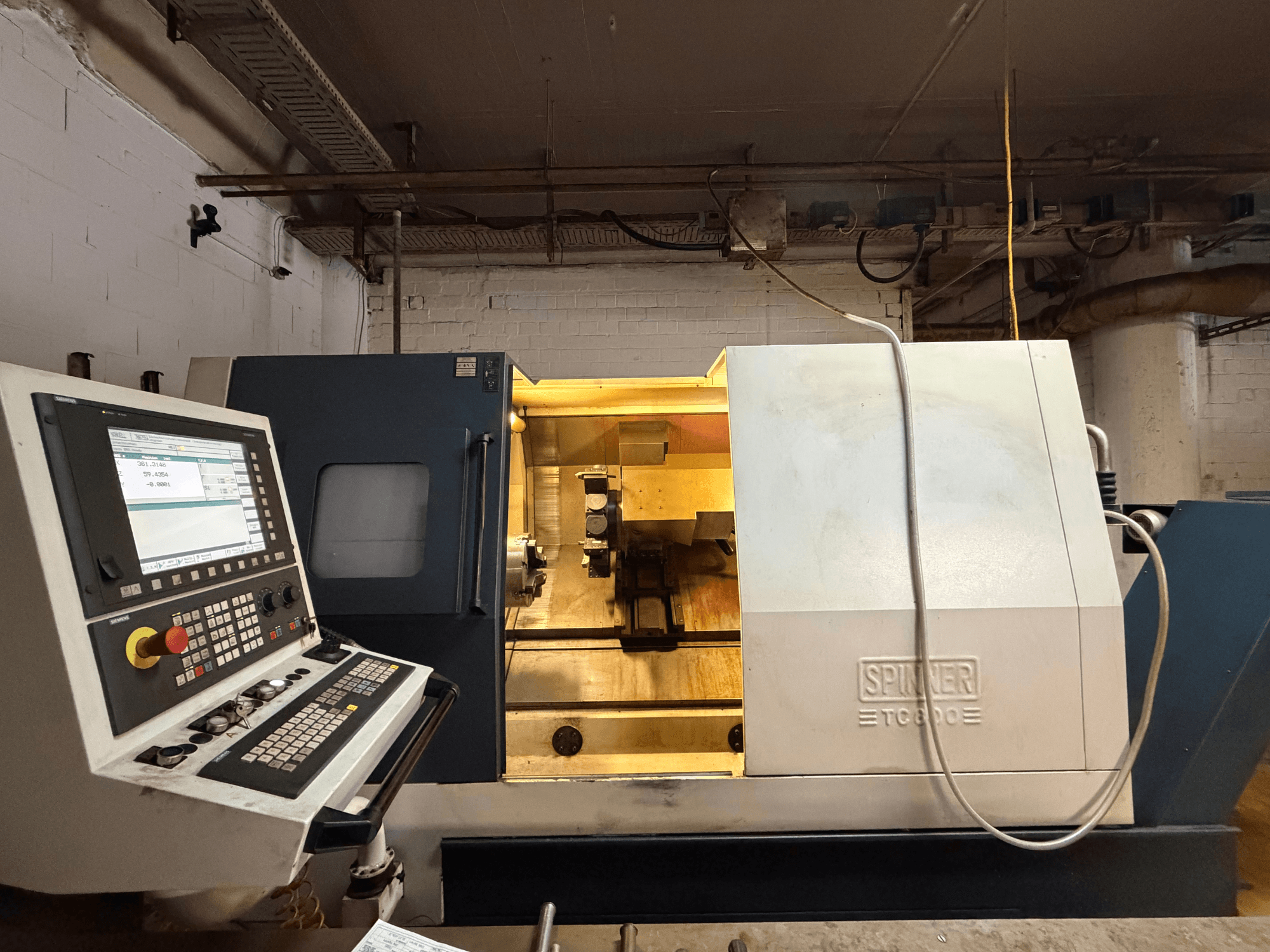 Tour horizontal SPINNER TC800 dans un atelier, avec panneau de commande et composants internes visibles.