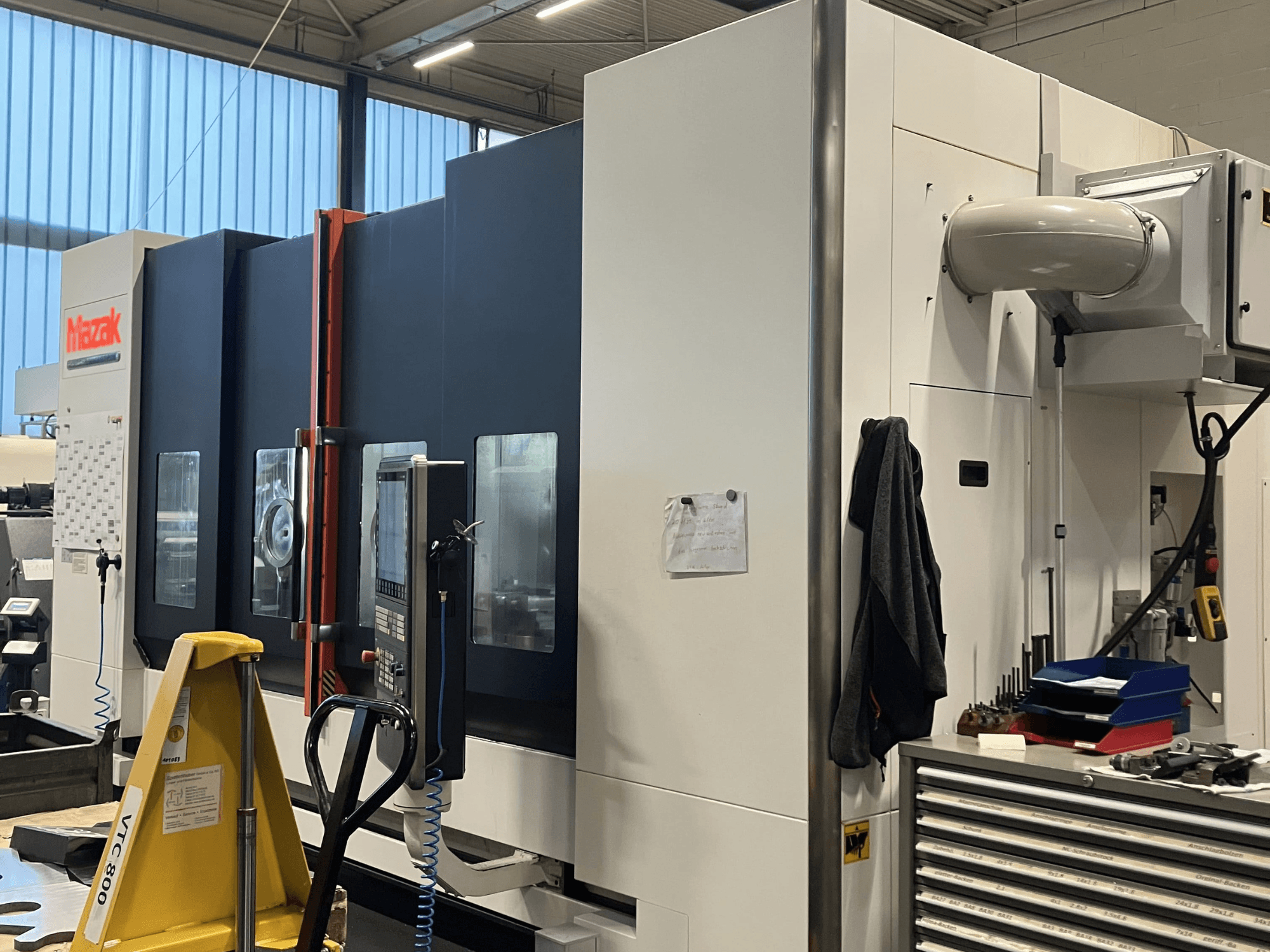 Machine CNC Mazak vue de côté, présentant le panneau de commande et les dispositifs de sécurité dans un atelier.