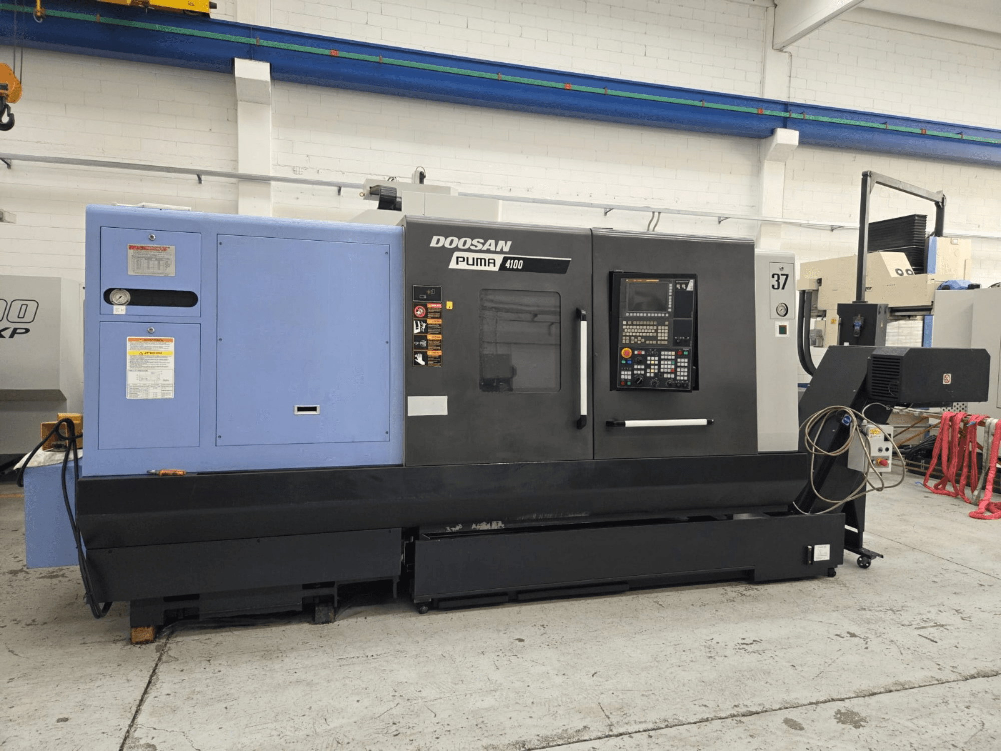 Tour CNC Doosan Puma 4100, vue de face ; comprend un panneau de commande, une unité d'alimentation bleue et des étiquettes détaillées pour le guidage opérationnel.