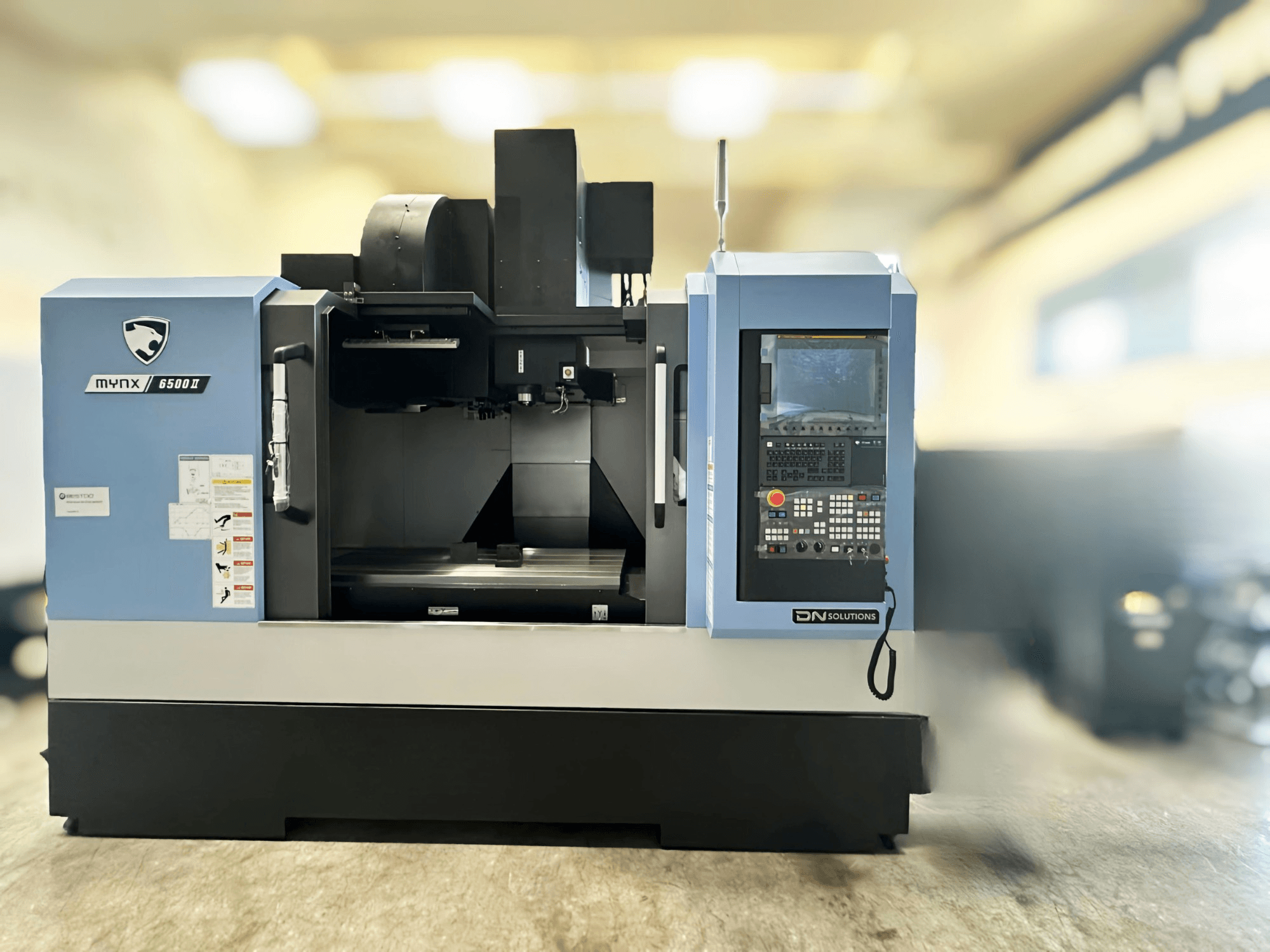 Centre d'usinage vertical DN SOLUTIONS MYNX 6500 II, vue de face montrant le panneau de commande et la zone de travail.