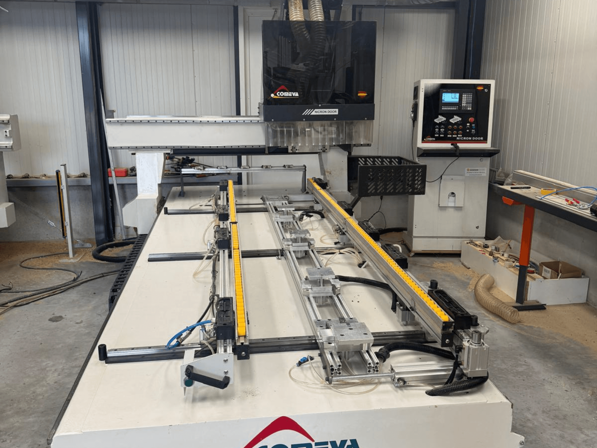 Centre d'usinage CNC du bois COMEVA MEX V 2100 x 3260, vue de face, comprenant un poste de travail, un panneau de commande et des rails de guidage.