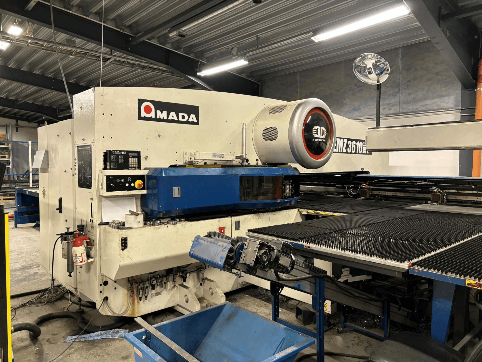 Poinçonneuse Amada EMZ3610H vue de l'avant ; comprend les commandes opérationnelles, le lit bleu et l'équipement de sécurité.