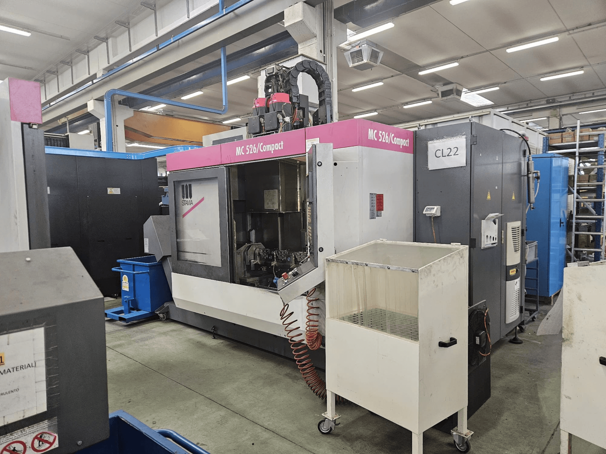 Machine CNC compacte MC 526 de Stama, vue latérale, montrant le panneau de commande, le réservoir de liquide de refroidissement et les machines adjacentes.