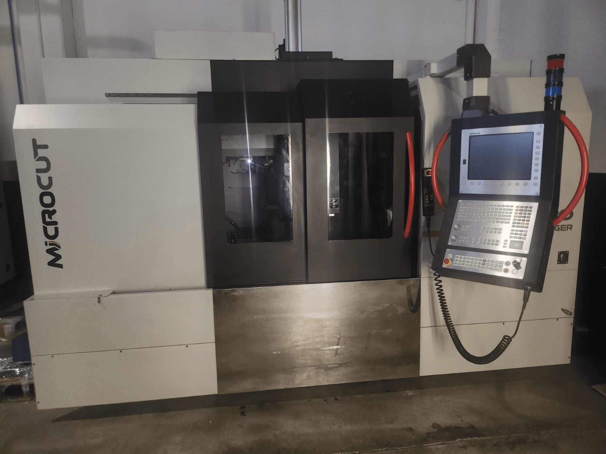Machine CNC Microcut vue de face ; elle présente un panneau de commande, deux fenêtres, un design industriel et une finition métallique.