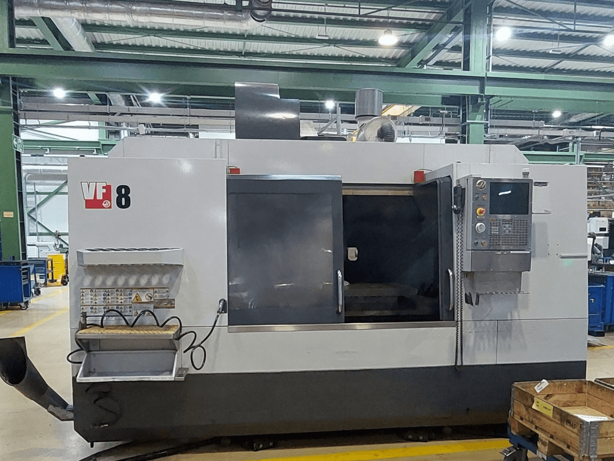 Centre d'usinage vertical HAAS VF-8, vue de face ; il comprend un panneau de commande et une zone de chargement, et est conçu pour des opérations d'usinage de précision.