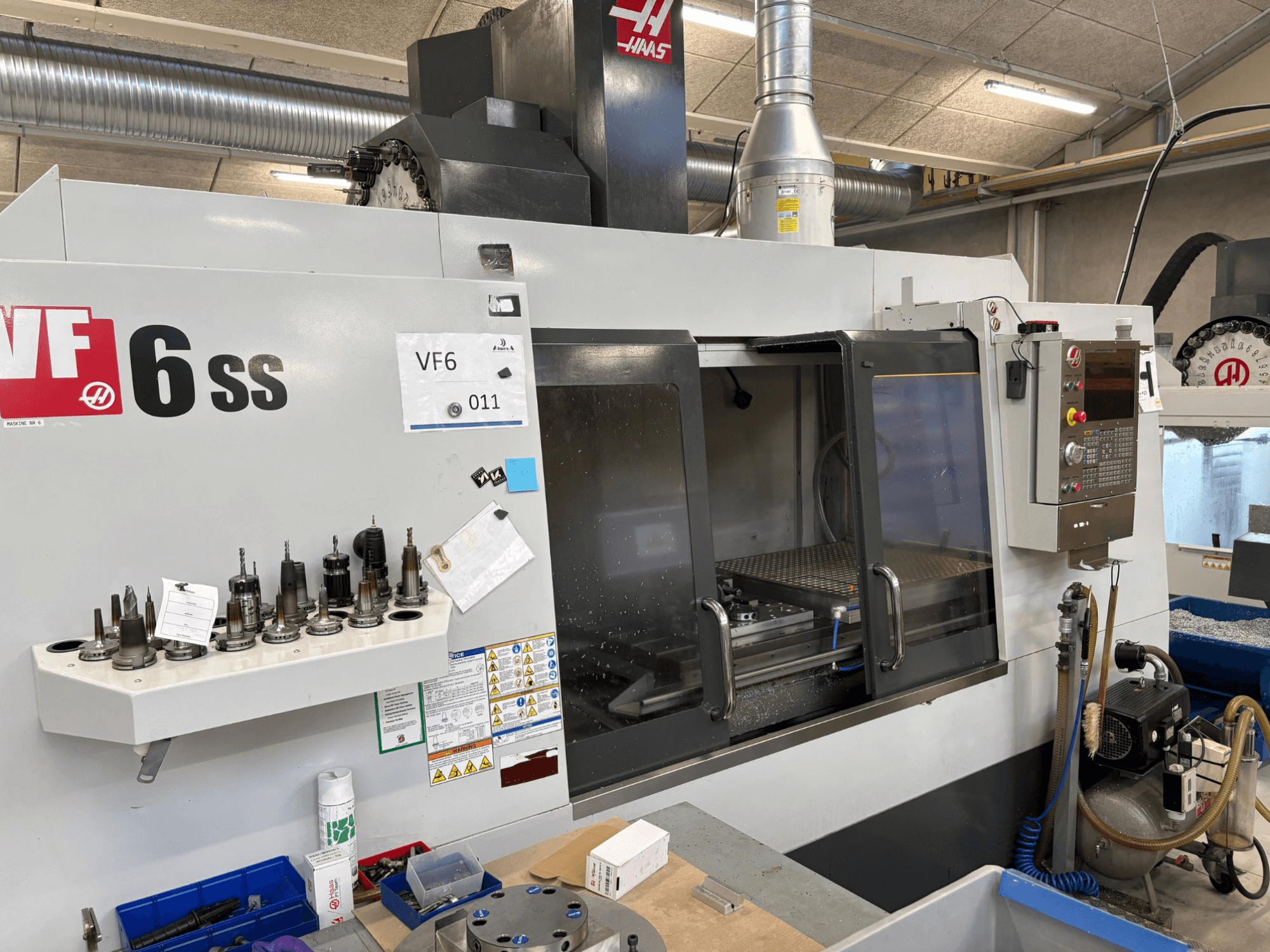 Fraiseuse CNC Haas VF-6 SS, vue de face. Comprend divers outils, un panneau de commande et un espace de travail interne visible.