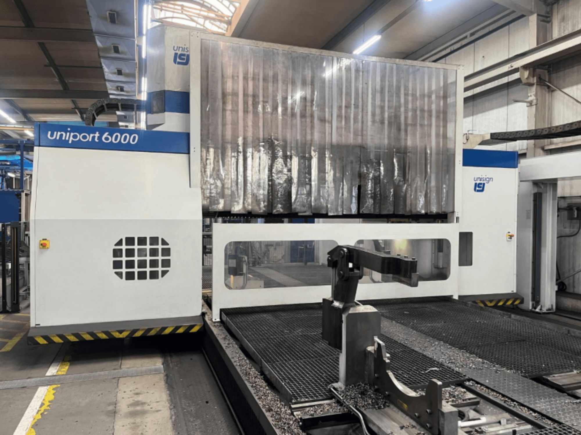 Fraiseuse à portique Unisign uniport 6000, vue de face, montrant la structure de la machine et la zone de coupe avec des copeaux de métal.