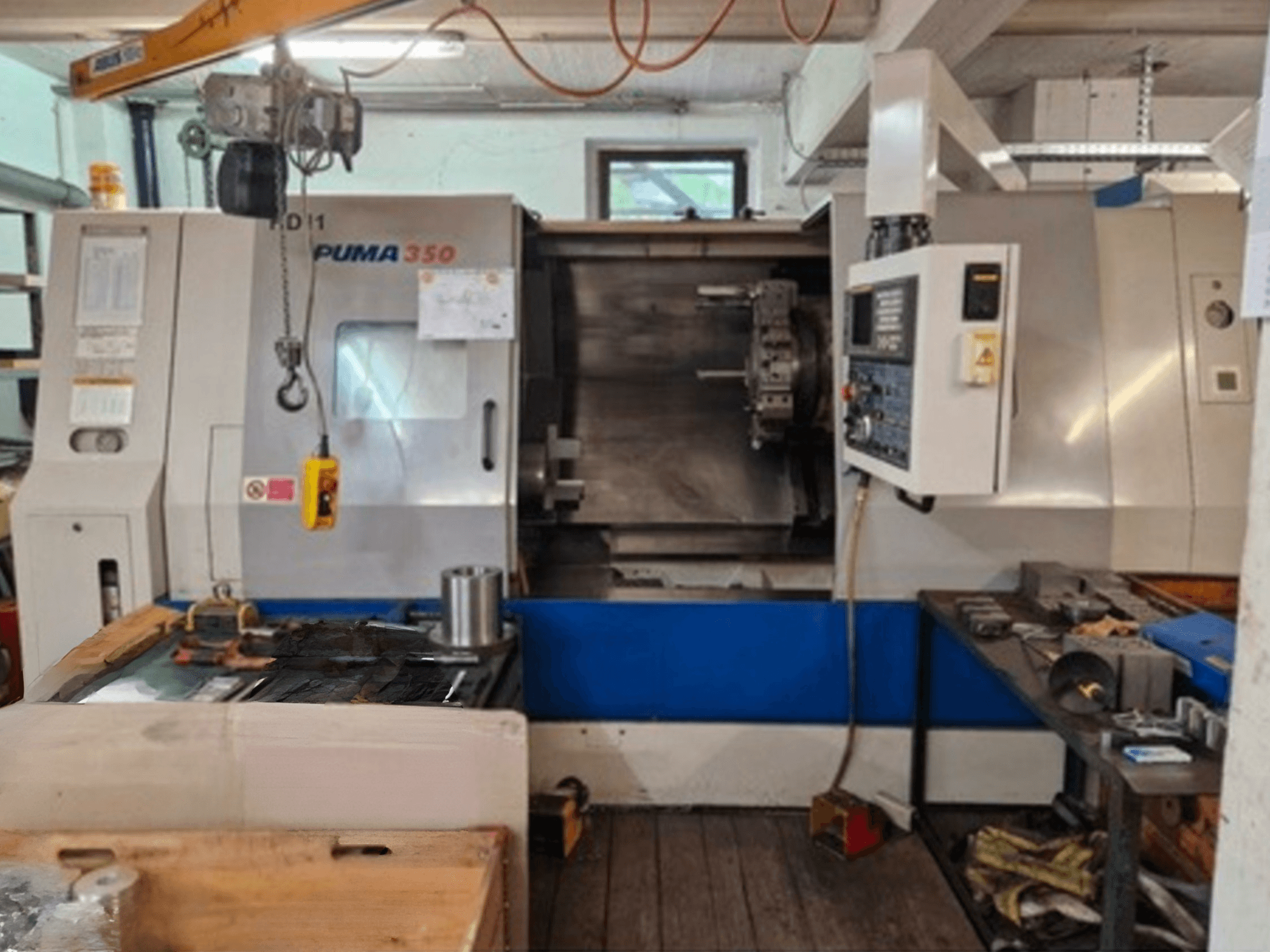 Tour horizontal DAEWOO Puma 350, vue latérale, montrant le panneau de commande et la zone de travail avec les outils et les matériaux à proximité.