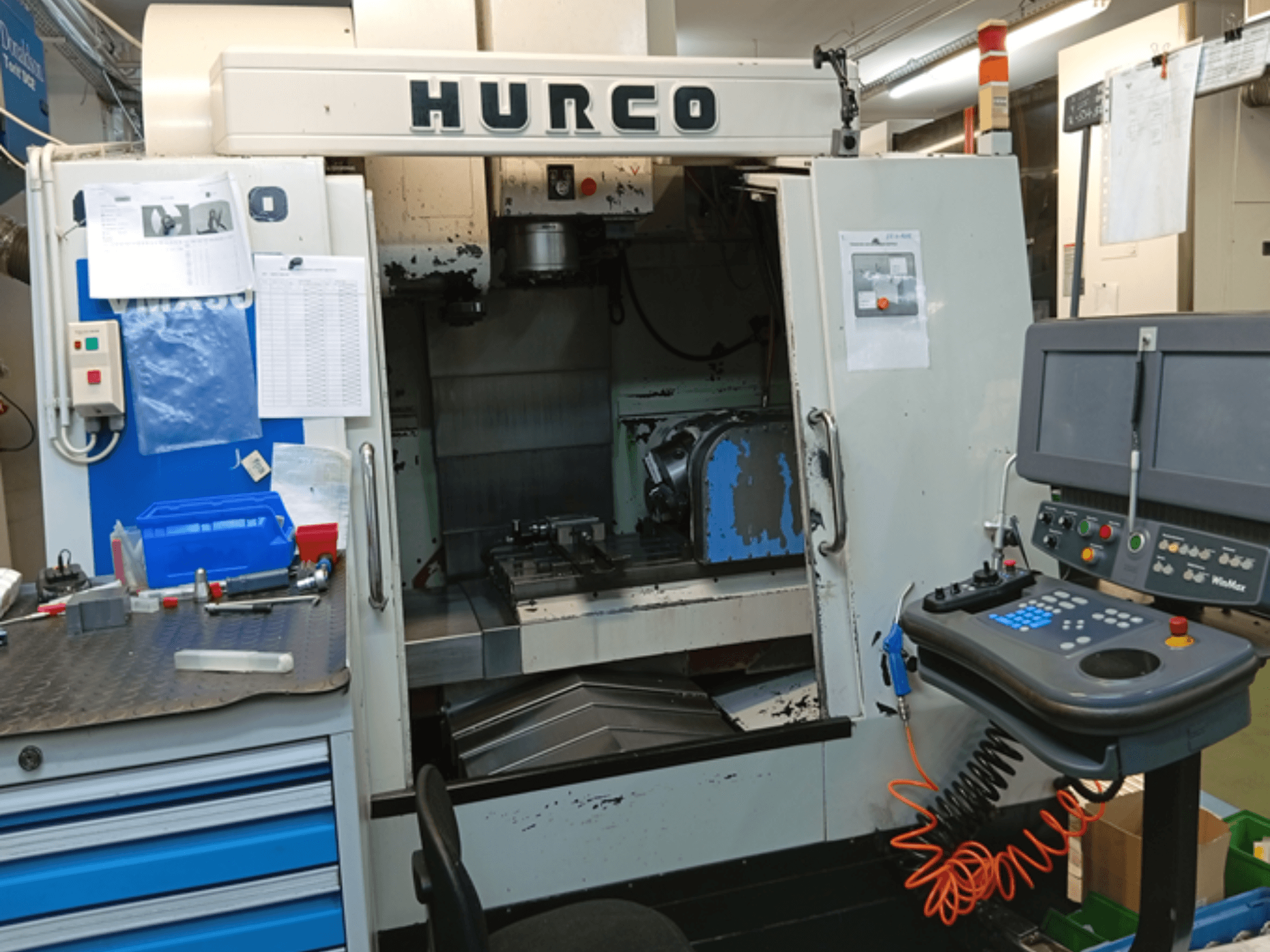 Centre d'usinage vertical Hurco VMX 30T, vue de face, montrant le panneau de commande, l'espace de travail et la porte partiellement ouverte.
