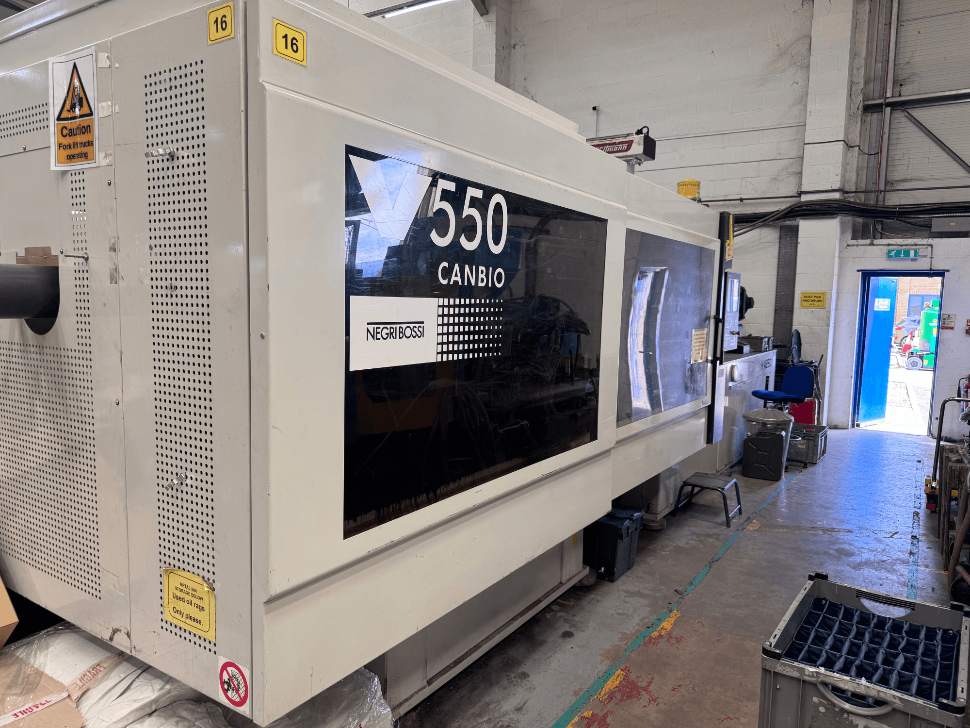 Presse à injection hydraulique Negri Bossi 5500H-4250, vue de face montrant le tableau de commande et les panneaux d'avertissement.