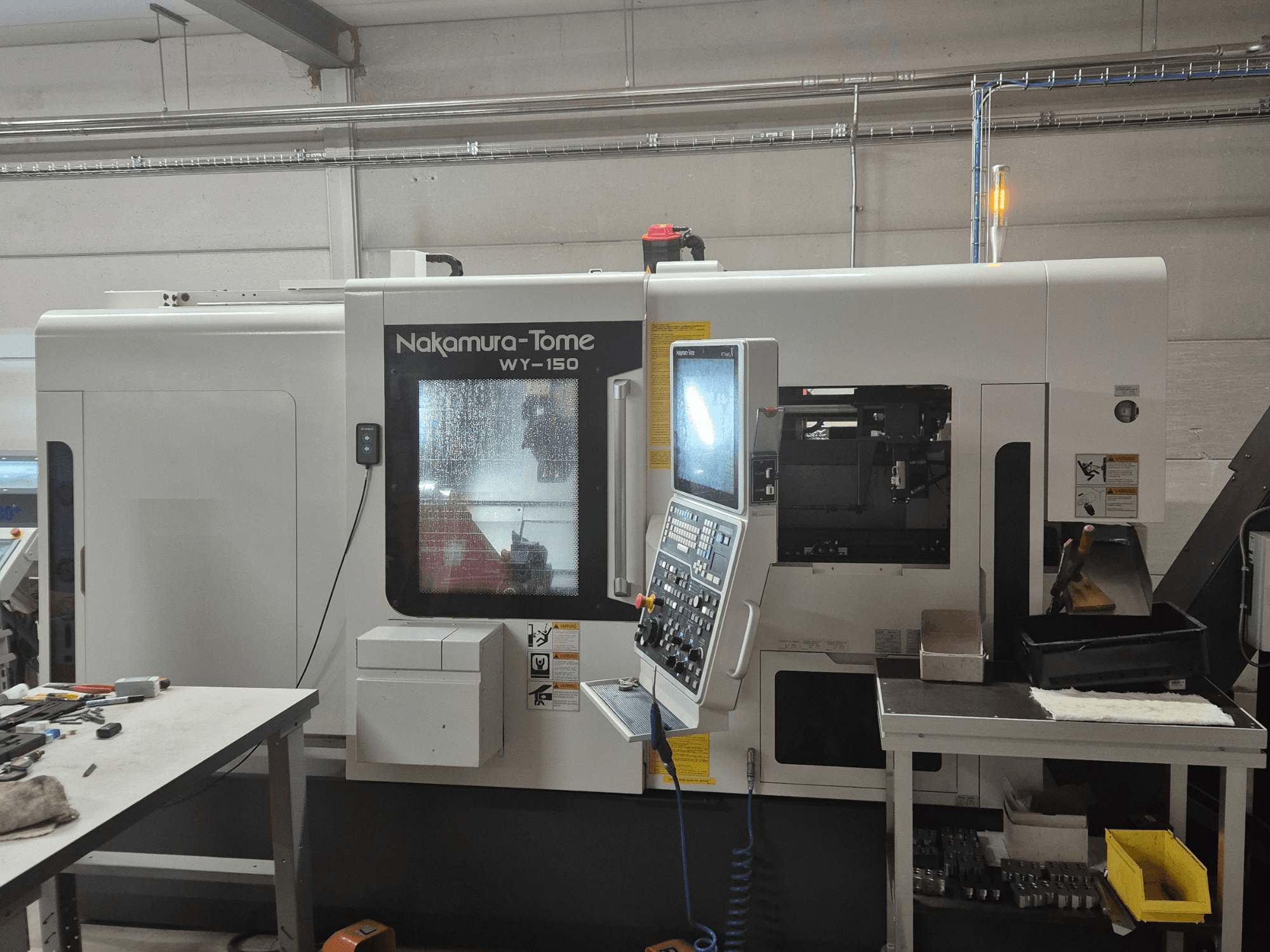 Tour CNC WY-150 de Nakamura-Tome en vue latérale, avec panneau de commande, fenêtre transparente et zone de travail visible.
