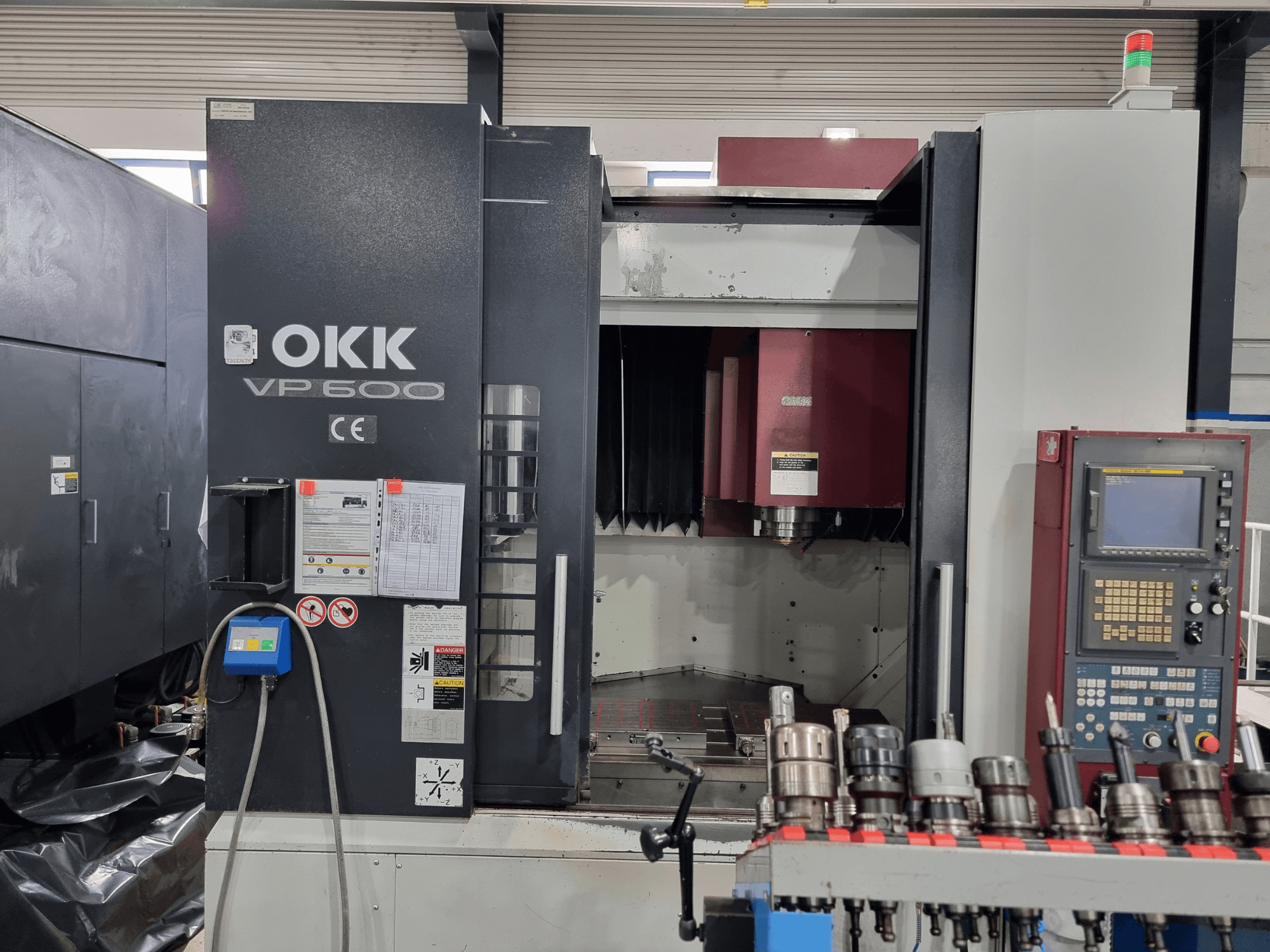Centre d'usinage vertical OKK VP600 vu de face, mettant en évidence le panneau de commande et les porte-outils montés sur un rail.