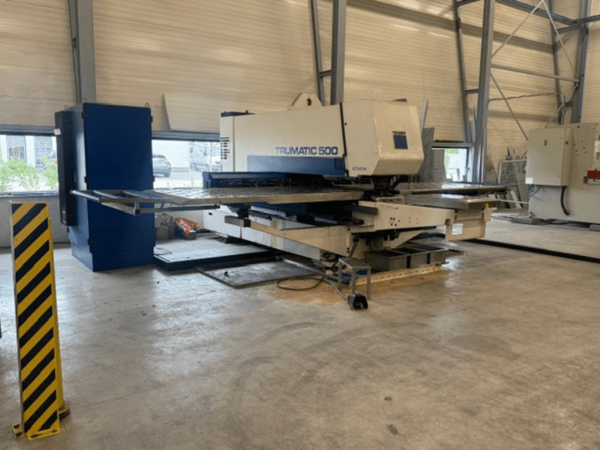 Poinçonneuse à commande numérique TRUMPF Trumatic 500 dans un atelier ; vue de profil montrant la machine et le poteau de sécurité rayé de jaune.