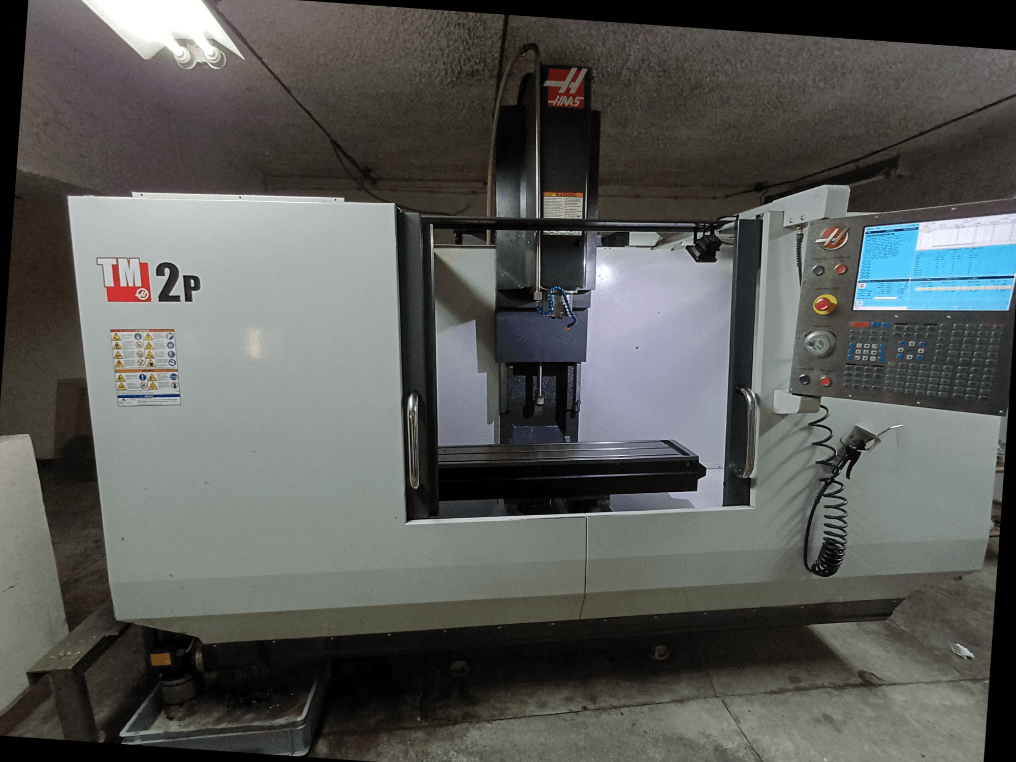 Centre d'usinage vertical HAAS TM-2P, vue de face, montrant le panneau de commande, la tête de la broche et le banc de la machine.
