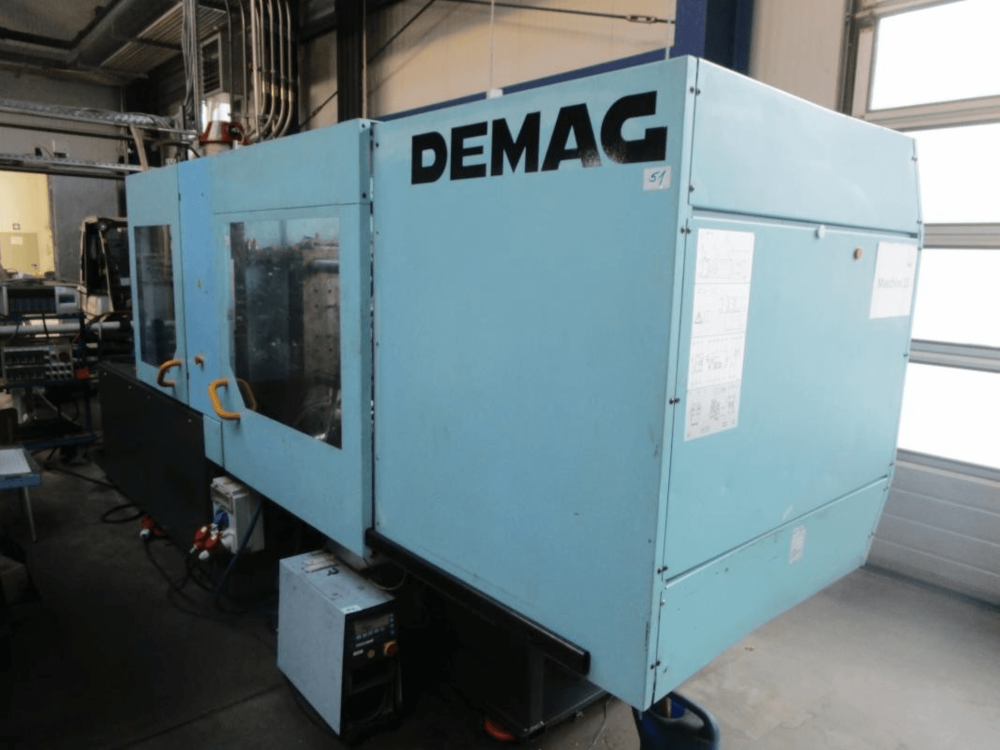 Vue de face d'une presse à injection hydraulique DEMAG Ergotech 150-610 Viva, avec le panneau de commande et les poignées bien visibles.