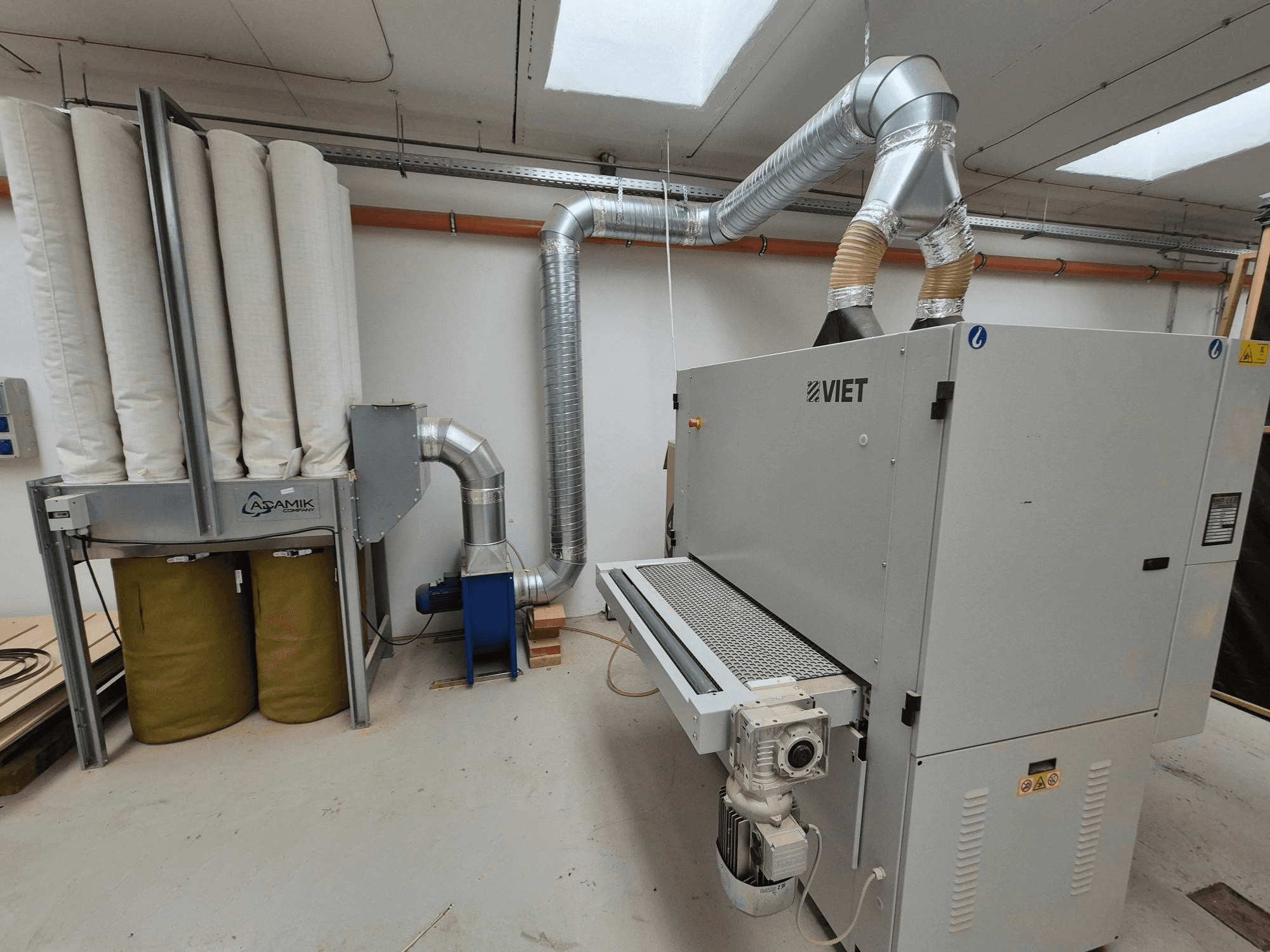 Système de dépoussiérage Viet doté de filtres cylindriques et d'un échappement argenté, vu de face dans un atelier.