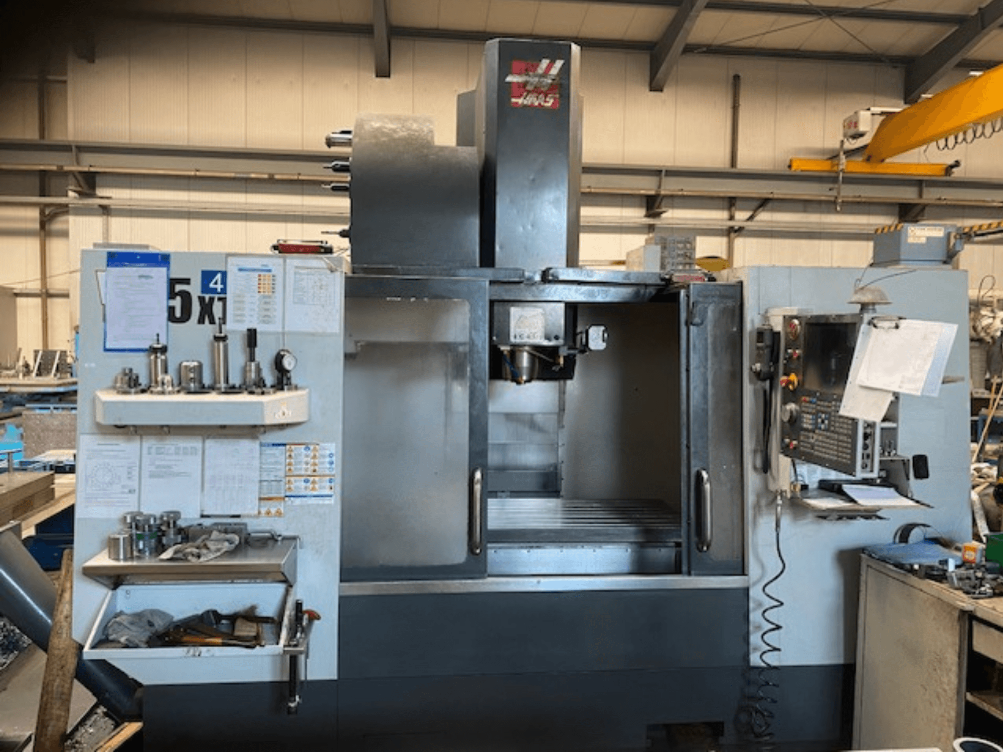 Centre d'usinage vertical Haas VF-5, vue de face, présentant le panneau de commande, le stockage des outils et la zone de la broche.