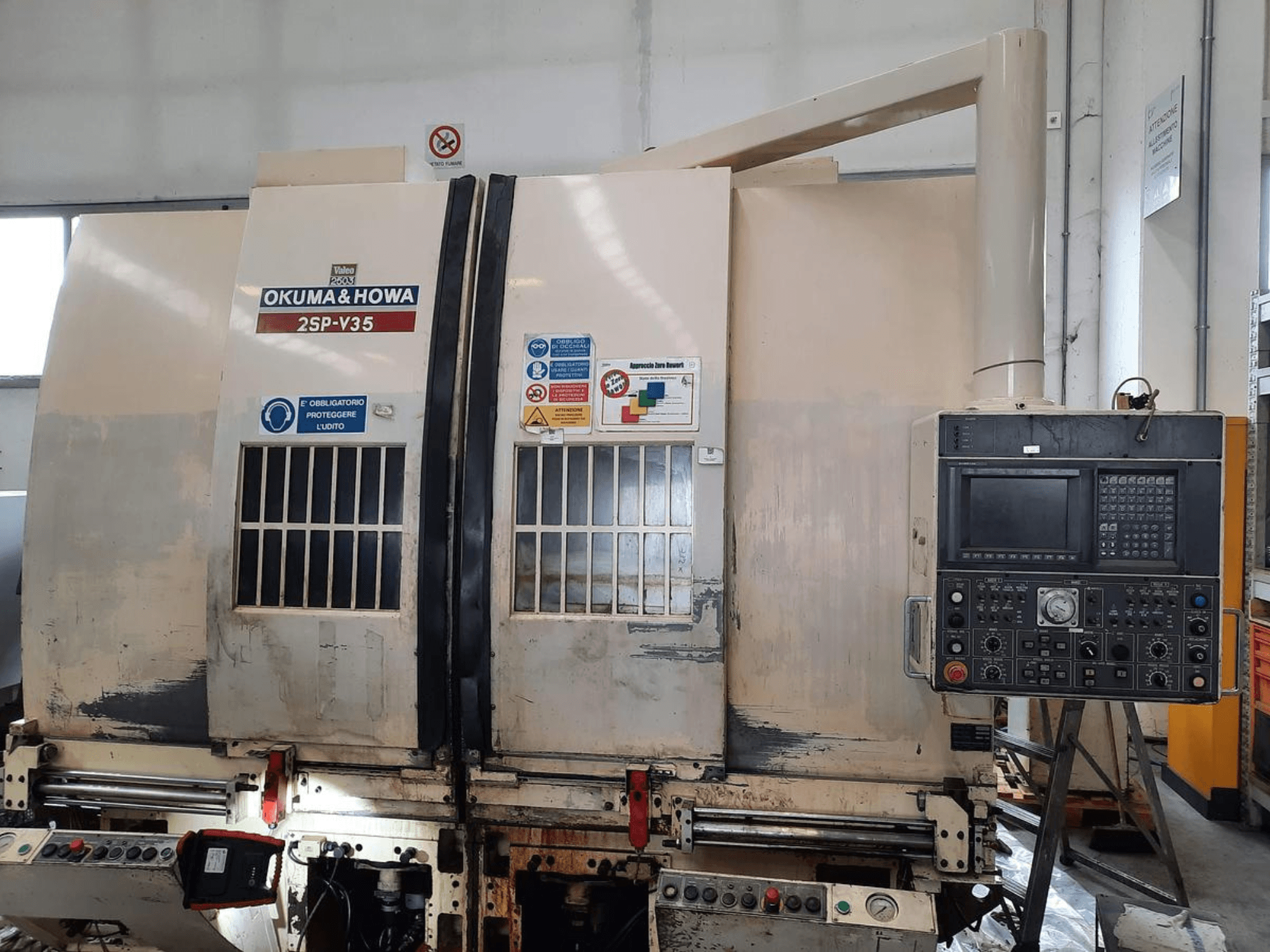 Machine CNC OKUMA & HOWA 2SP-V35 vue de face, avec panneau de commande comportant divers boutons et étiquettes de sécurité.