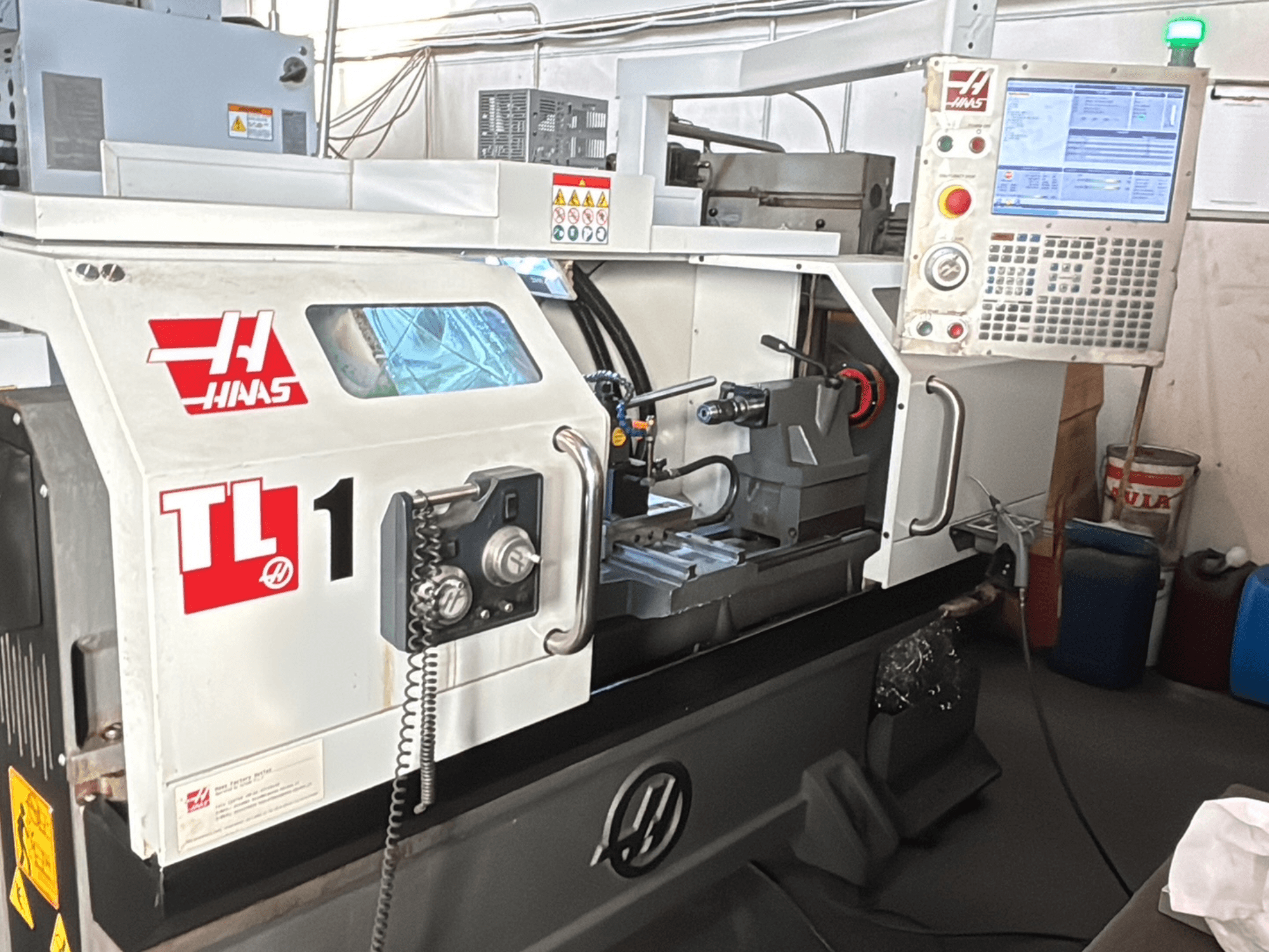 Tour CNC Haas TL-1, vue de face, panneau de commande avec écran, porte-outil et étiquettes de sécurité.