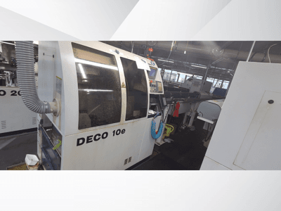 Machine DECO 10e dans un atelier ; vue latérale montrant le panneau de commande et le tuyau de ventilation, avec des machines floues à l'arrière-plan.