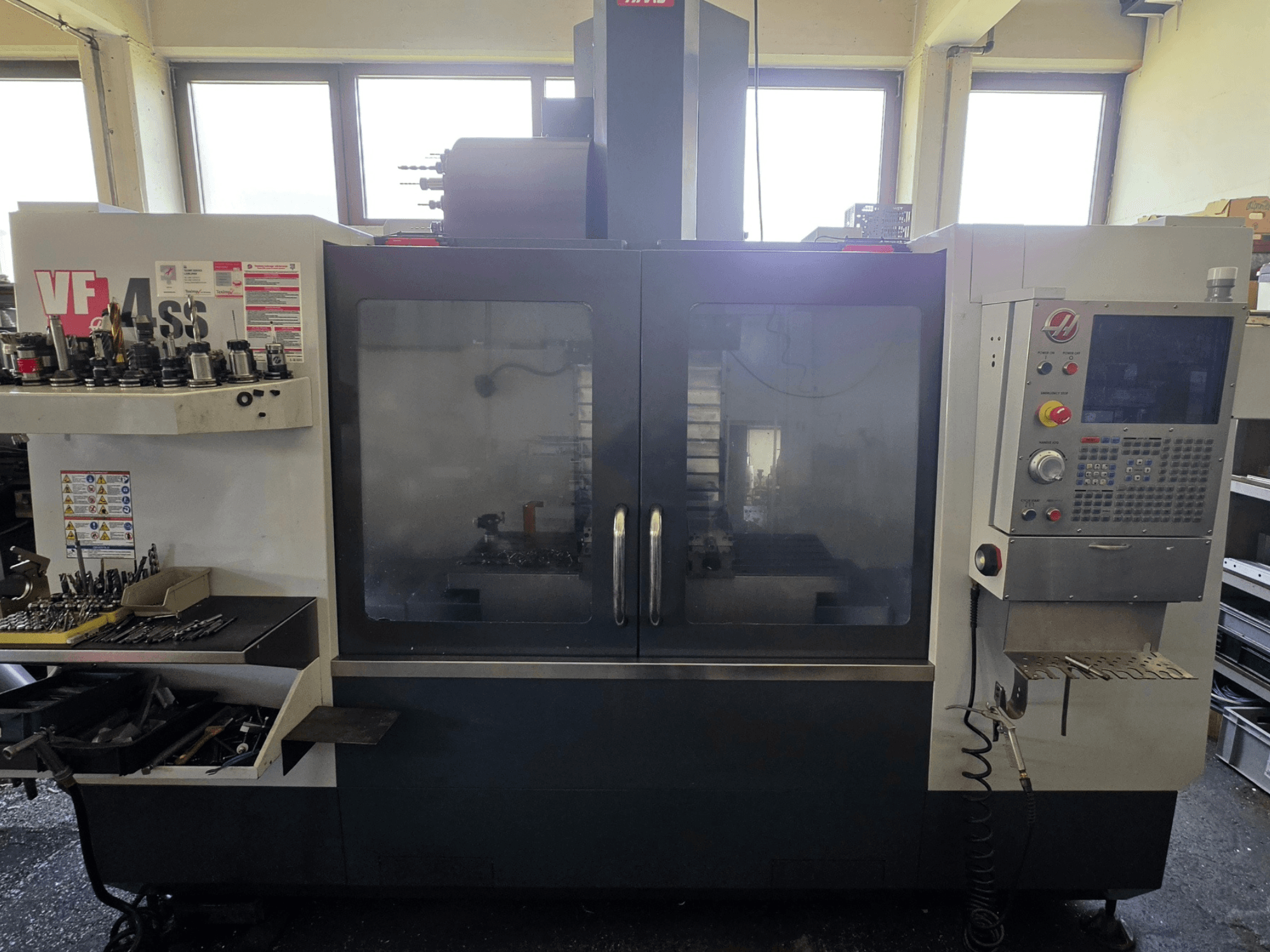 Vue avant du centre d'usinage vertical HAAS VF 34SS, montrant le panneau de commande et la zone de stockage des outils.