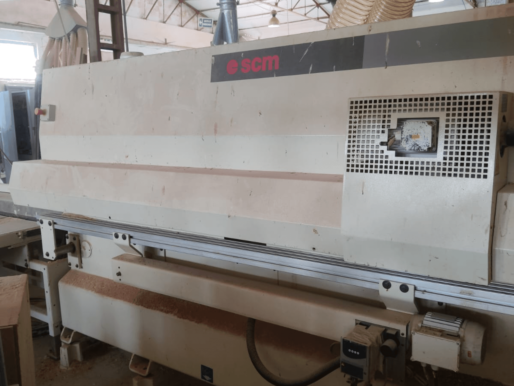 Centre d'usinage CNC pour le bois SCM Windor60, vue de face. On y voit les commandes de la machine et le système de dépoussiérage, avec des copeaux de bois au sol.