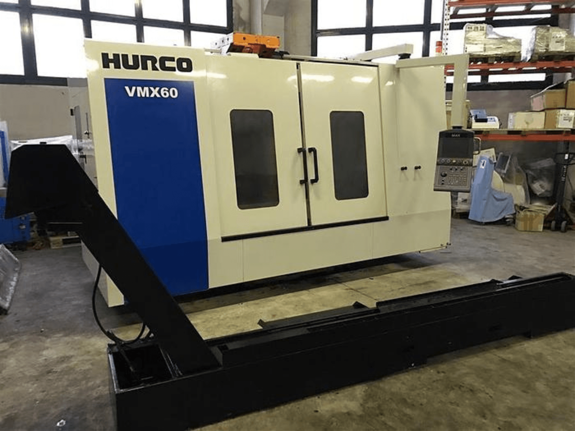Machine CNC HURCO VMX60 dans un atelier, vue de face, avec un panneau de commande et un rail de support noir.