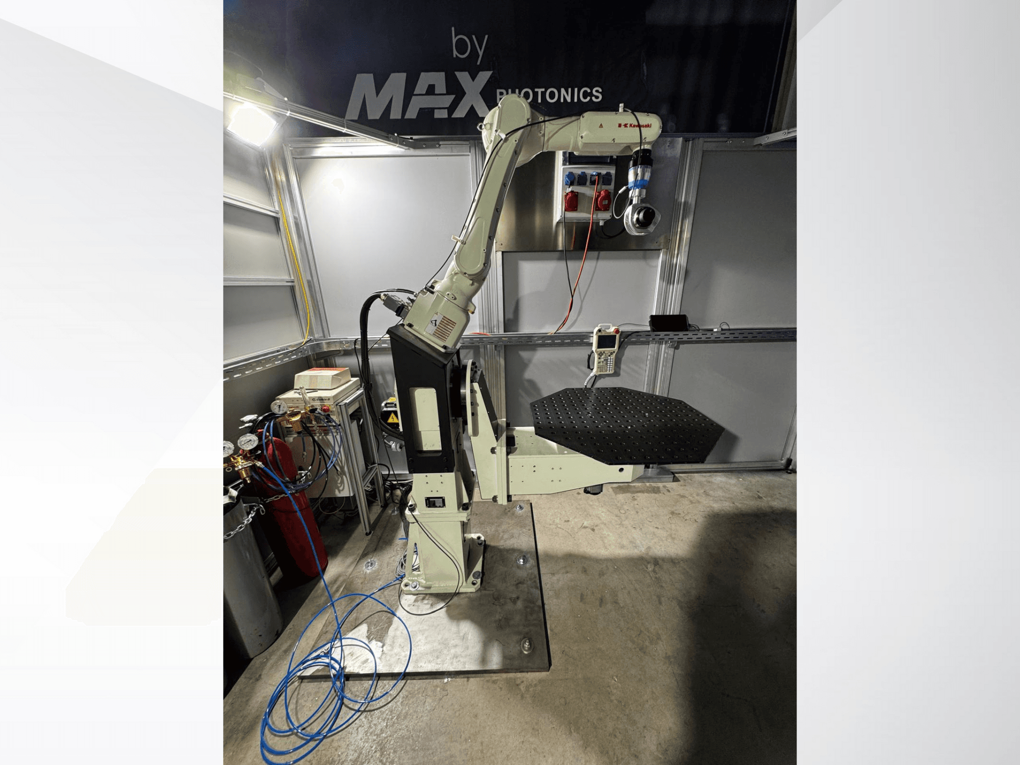 Bras robotique de Max Photonics, vue de face, comprenant une plate-forme noire perforée et un panneau de commande avec des jauges et des câbles.