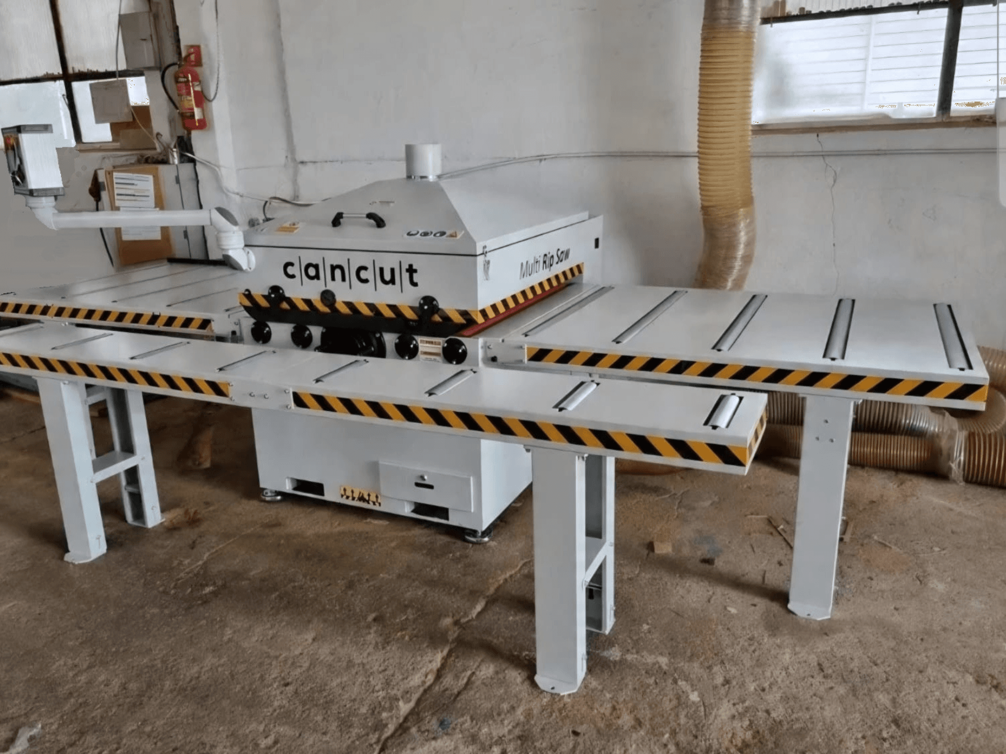 Scie circulaire à bois CAN CUT MC 930 équipée de deux tables à bandes de sécurité, vue de face dans un atelier intérieur.