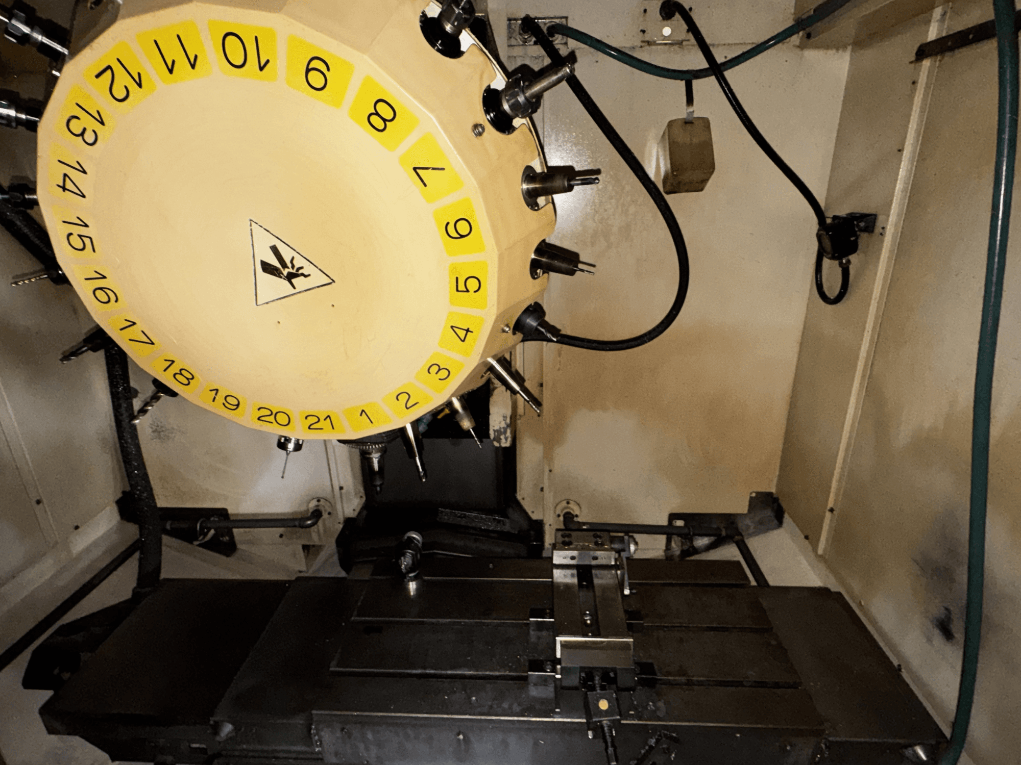 Vue intérieure du centre d'usinage vertical FANUC Robodrill alpha-T21iFL avec le carrousel d'outils et la table d'usinage visibles.