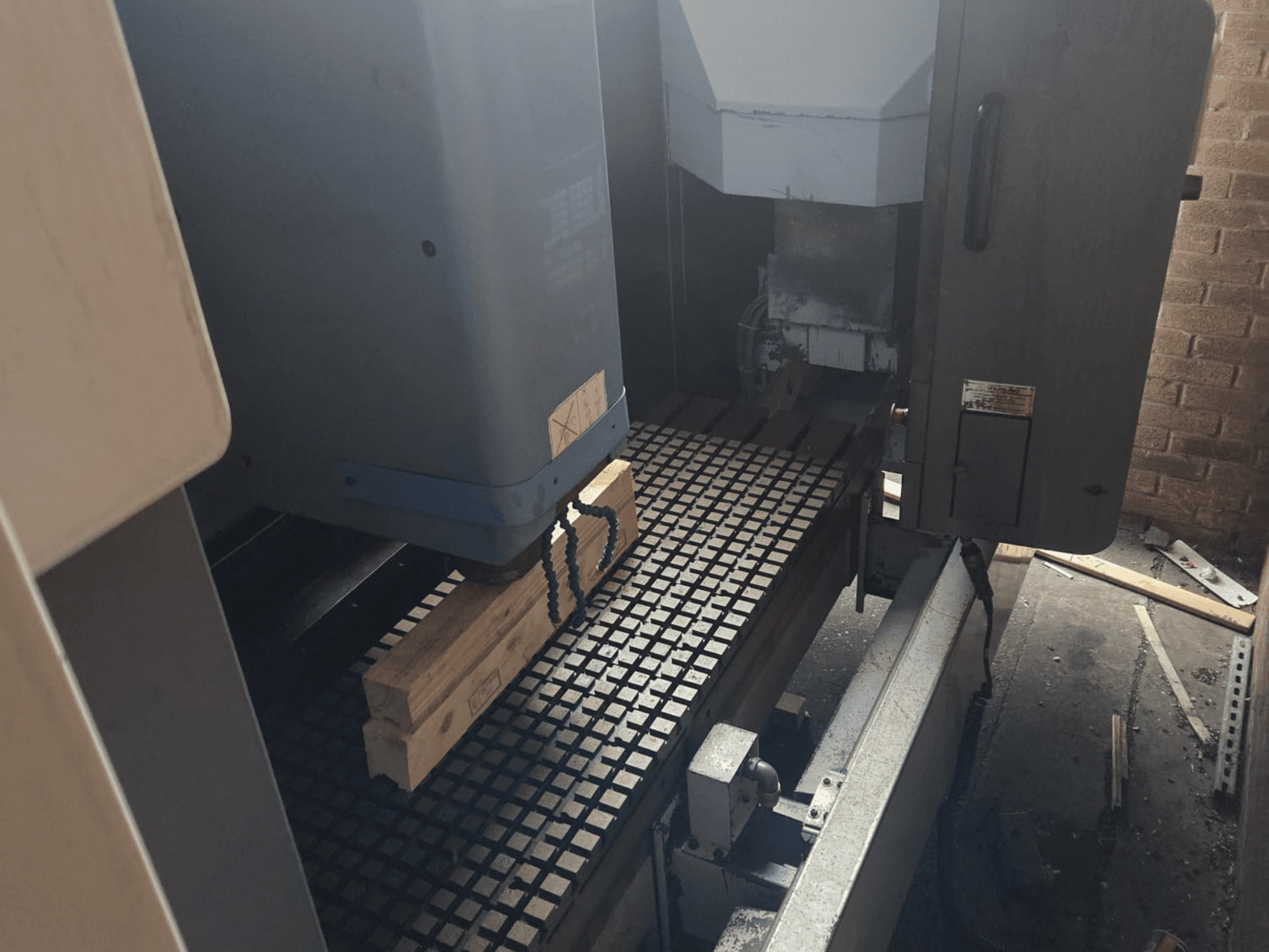 Machine CNC vue de face avec des planches de bois sur une table quadrillée, présentant les outils et les commandes sur le côté.