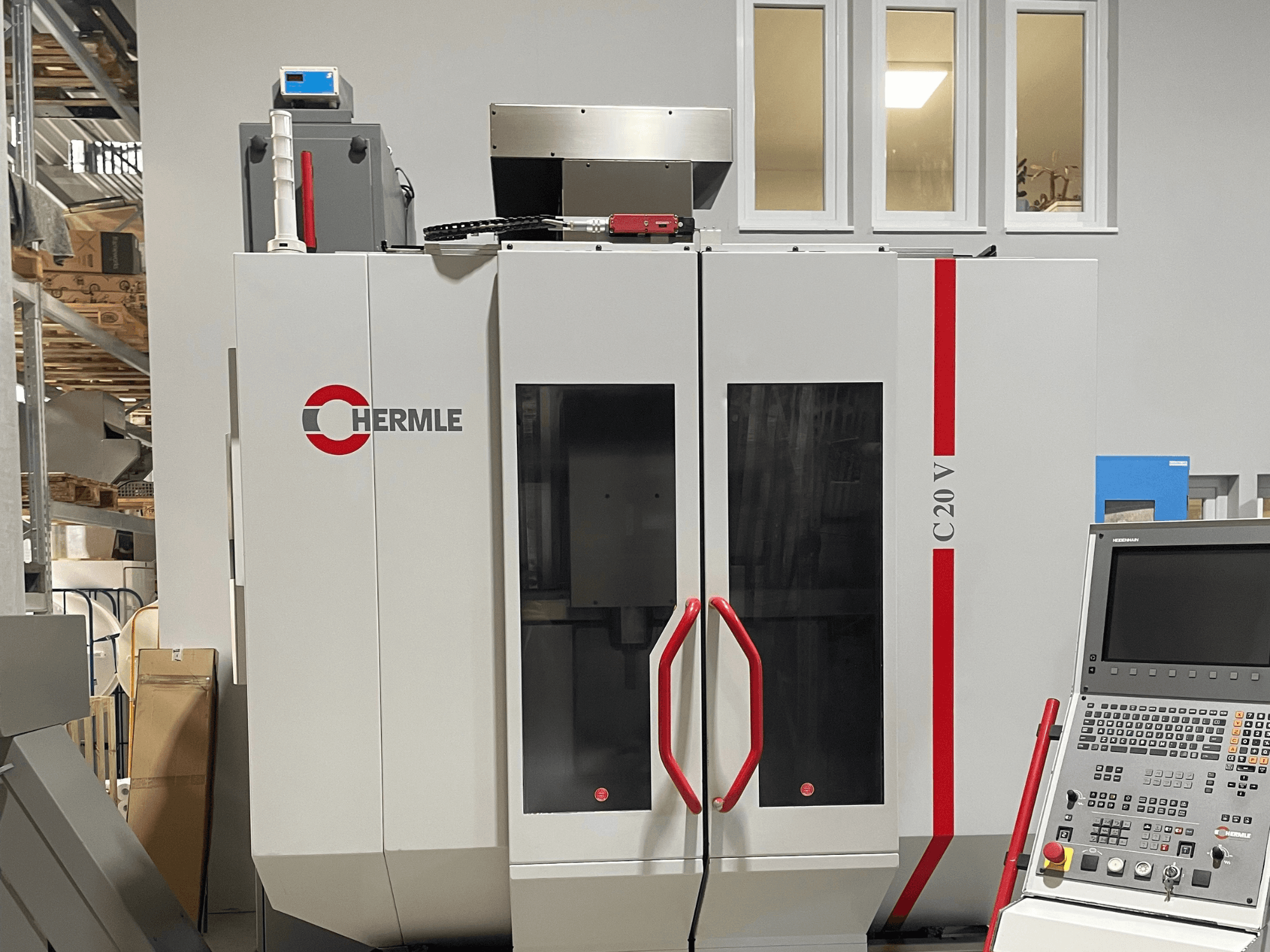 Machine CNC Chermle C20 V, vue de face, avec panneau de commande et poignées rouges ; design industriel avec grandes portes vitrées.