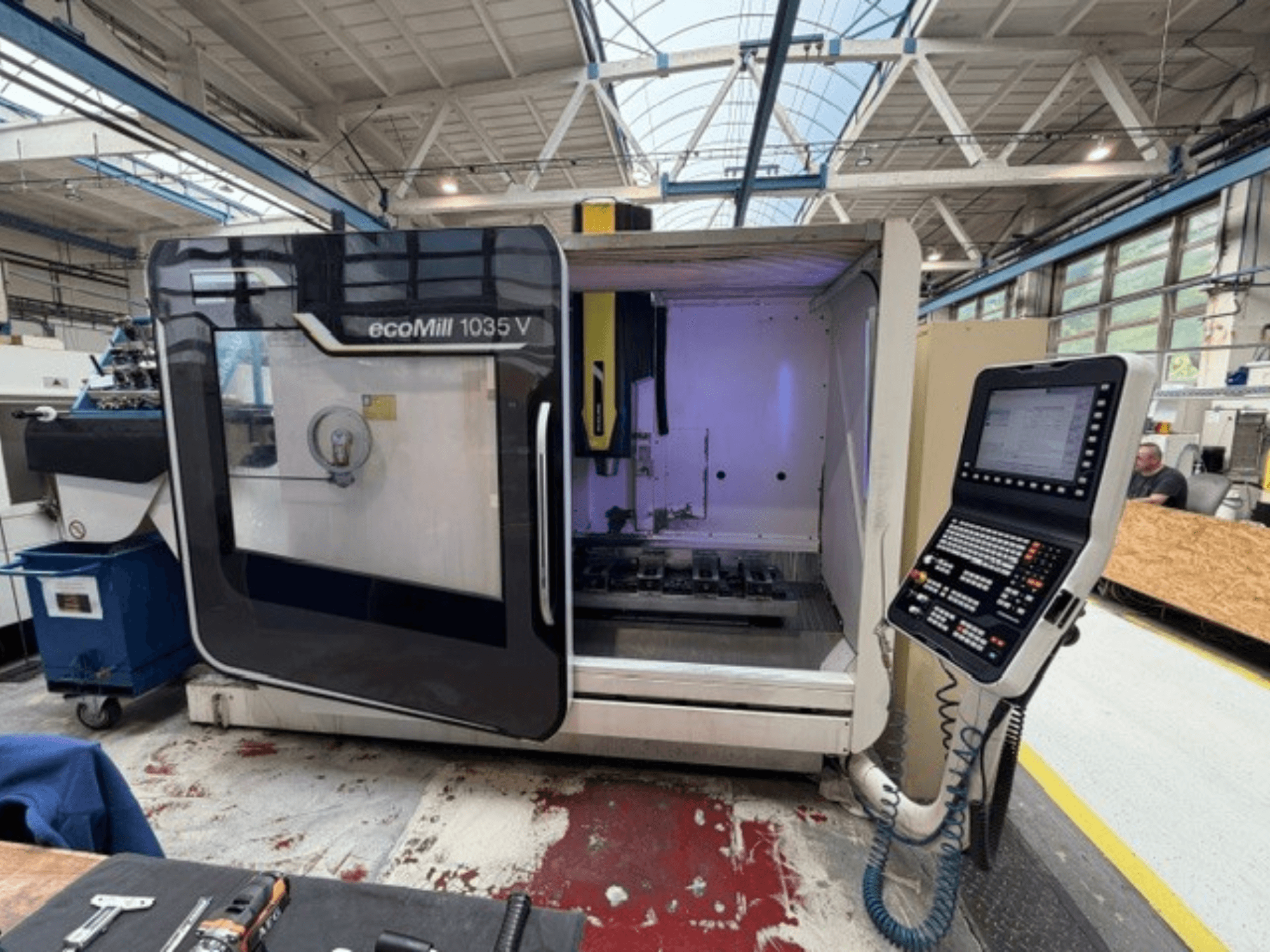 Vue de face du centre d'usinage vertical DMG MORI ecoMill 1035V, porte ouverte, montrant le panneau de commande et la zone de travail à l'intérieur.