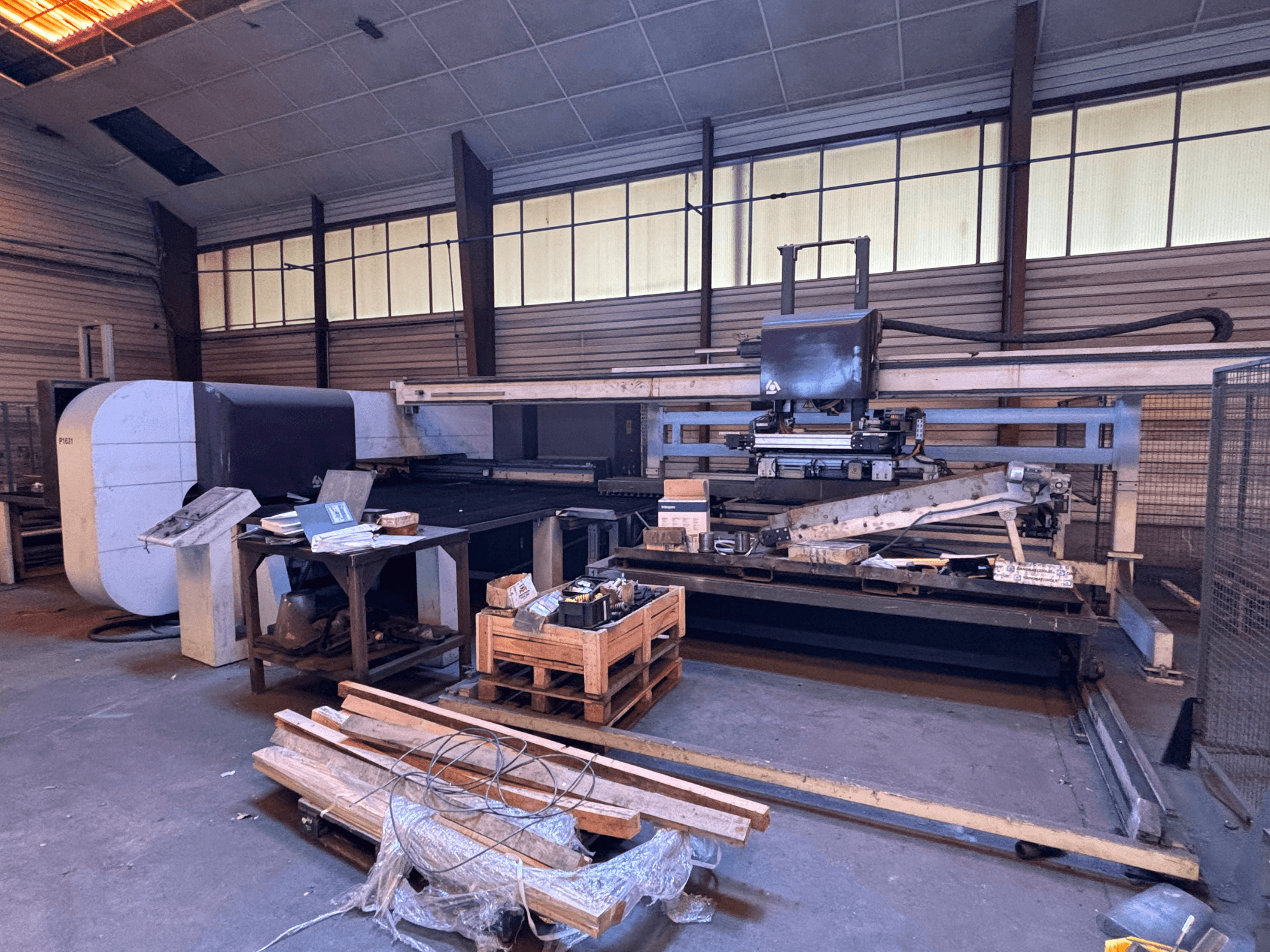Poinçonneuse CNC DANOBAT P1631 dans un atelier, vue de face, entourée de matériaux et d'outils sur un sol encombré.