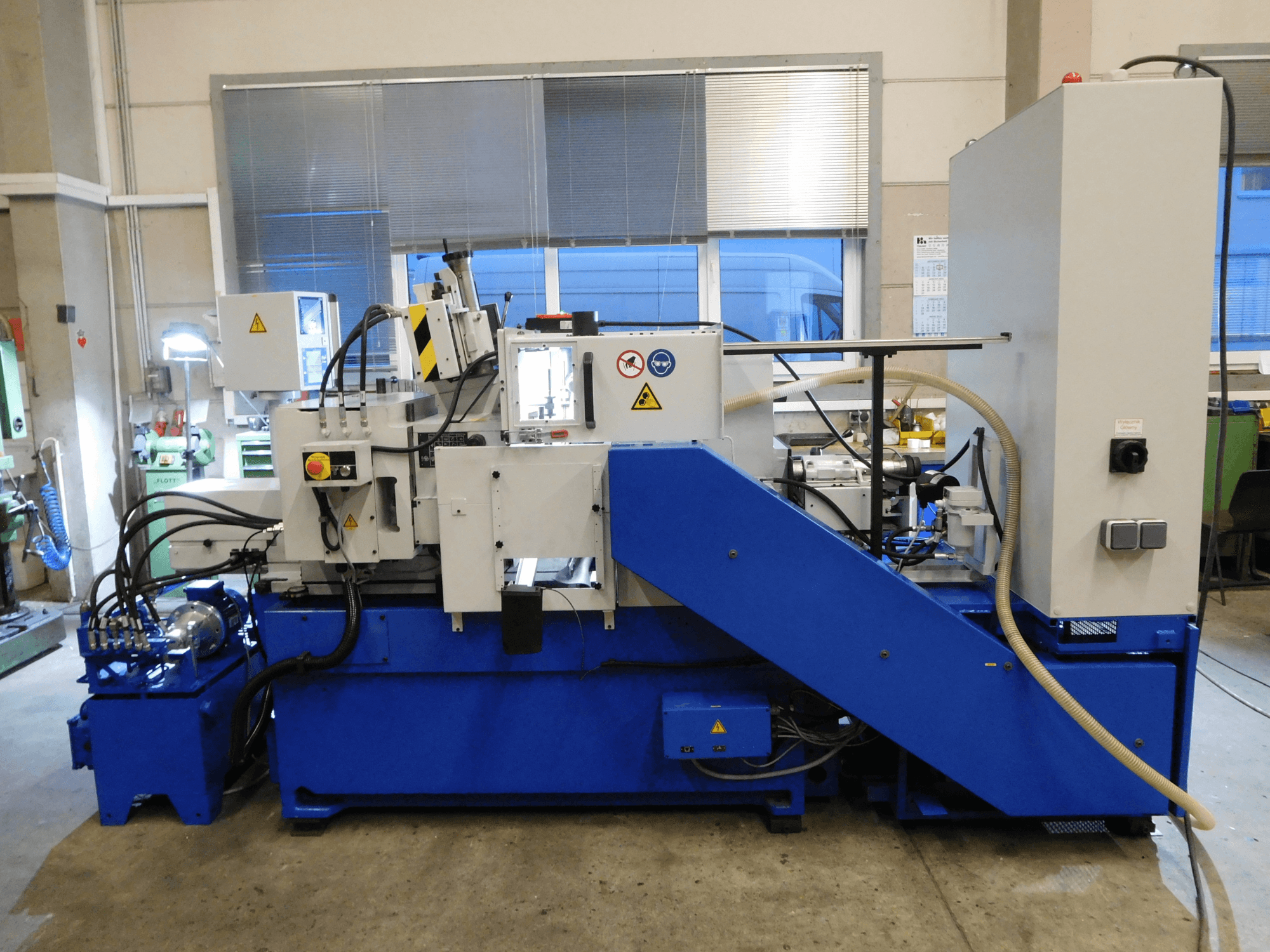 Machine à meuler sans centre Schaudt Mikrosa SASL 125, vue de côté, avec base et panneau de commande bleus, présentant les caractéristiques opérationnelles.